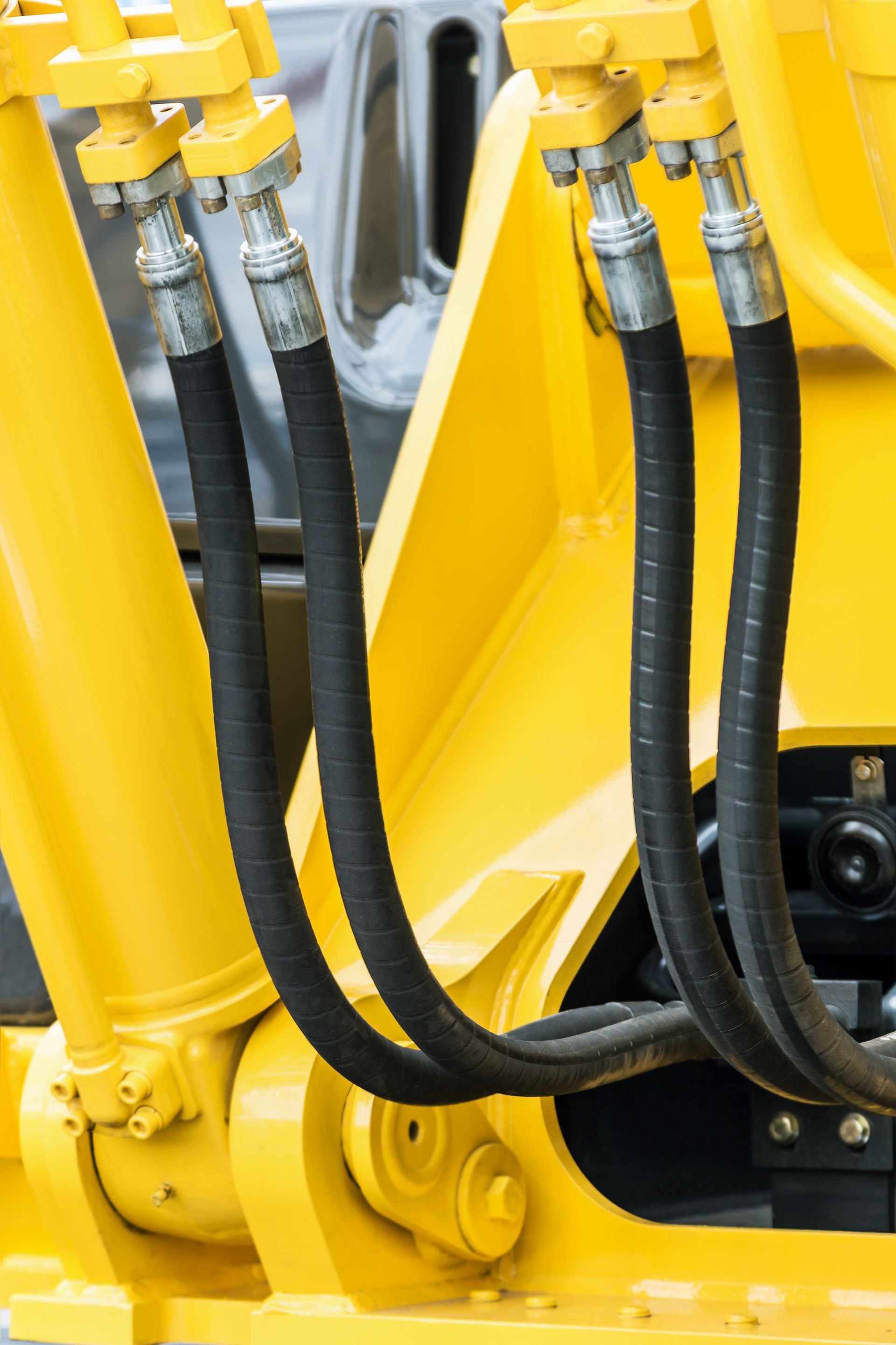 Hydraulic hoses and metal fittings attached to yellow heavy machinery equipment Hydraulic hoses and metal fittings attached to yellow heavy machinery equipment