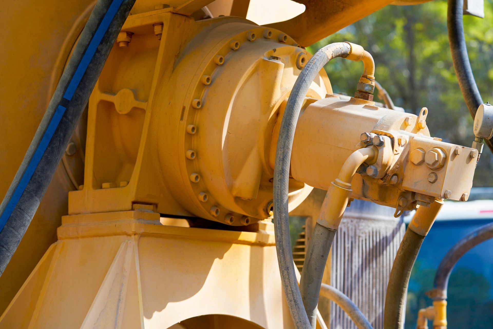 Close-up of yellow industrial machinery with hydraulic hoses.