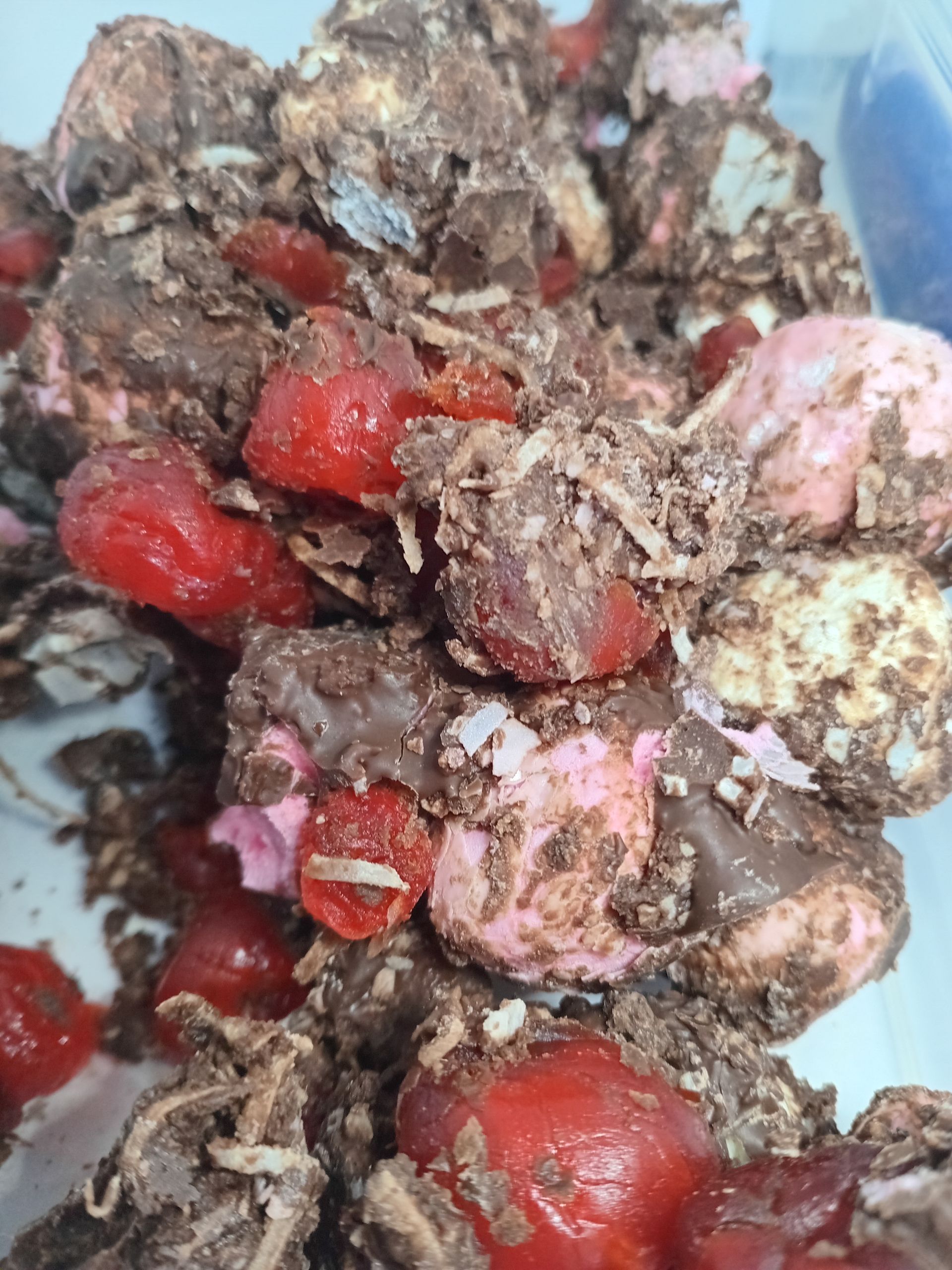 Rocky road candy with red cherries, pink and white marshmallows, and chocolate coating.