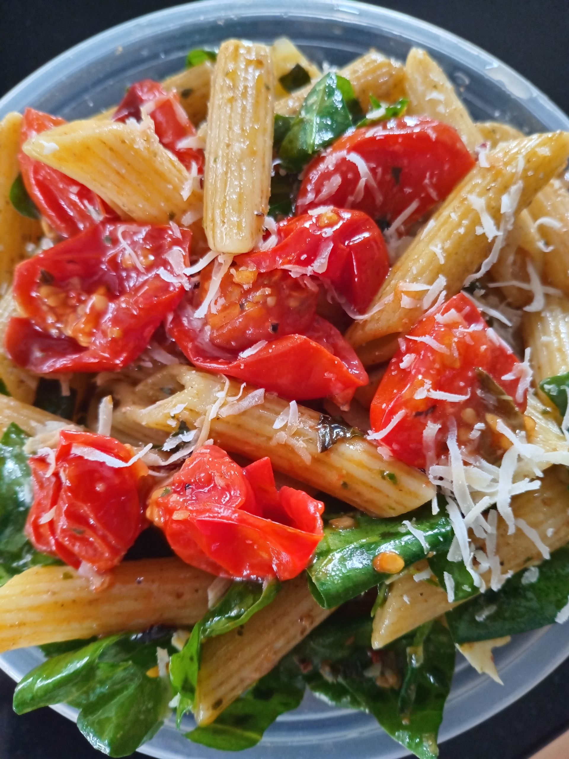 Pasta salad with tomatoes, spinach, and parmesan cheese.