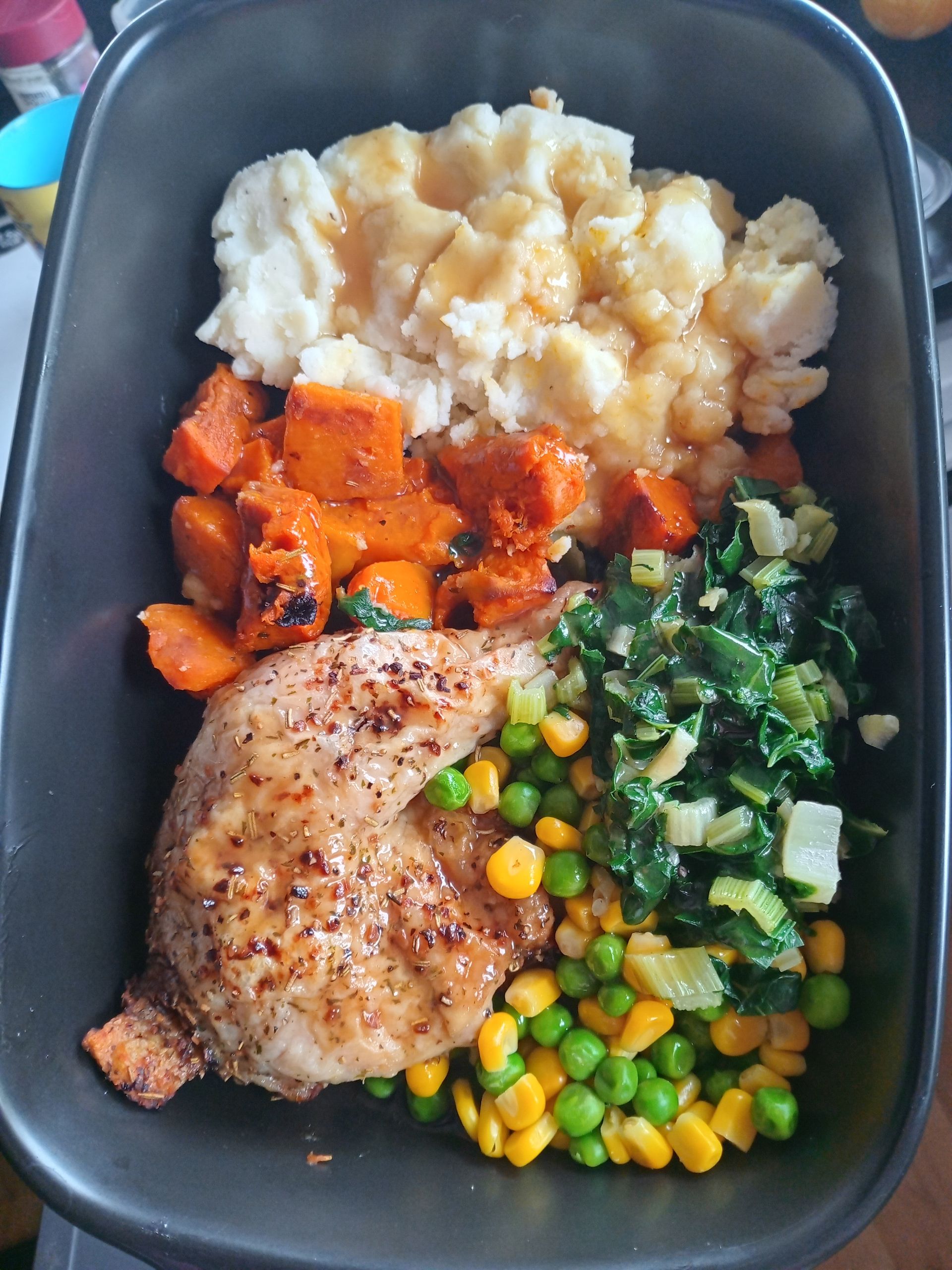 Meal prep container with grilled chicken, mashed potatoes with gravy, roasted sweet potatoes, and vegetables.