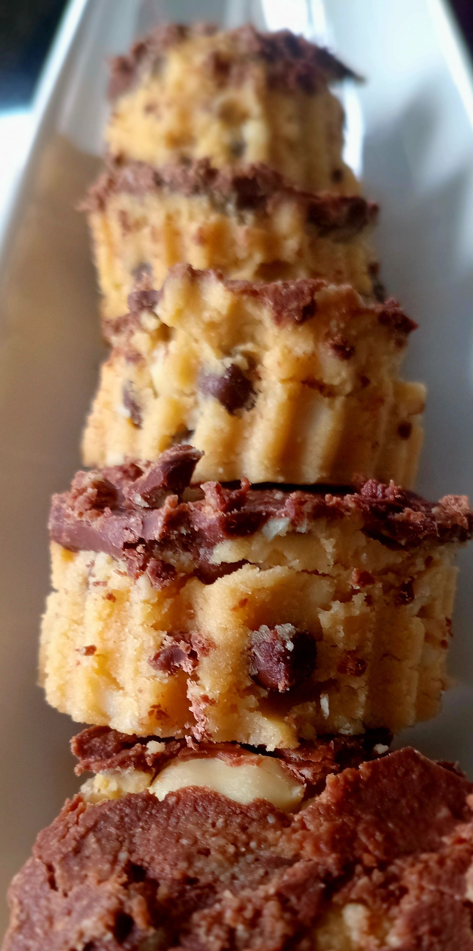 Close-up of stacked cookies with chocolate chips and topping on a white plate.