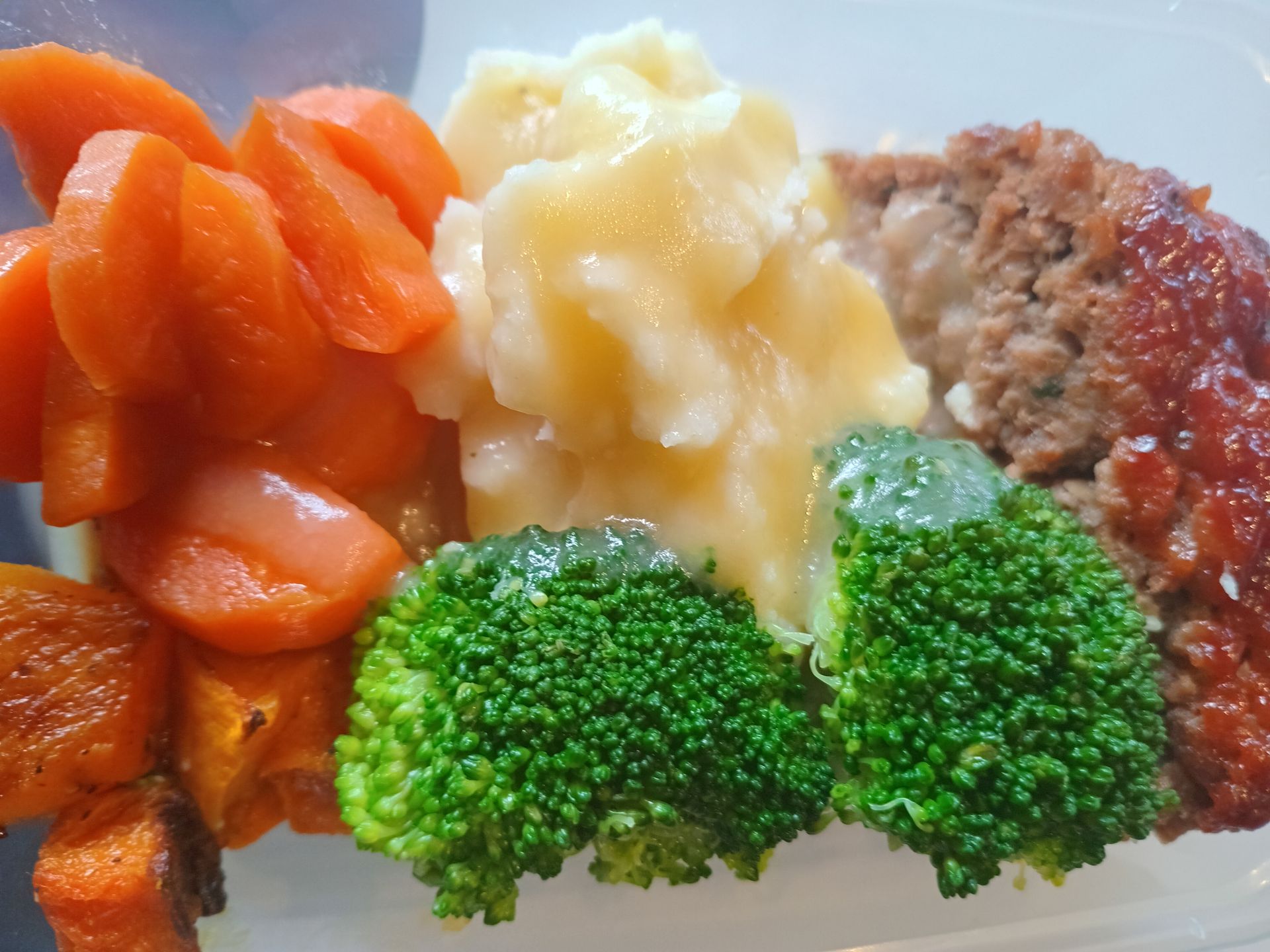 Meatloaf with carrots, mashed potatoes, and broccoli on a plate.