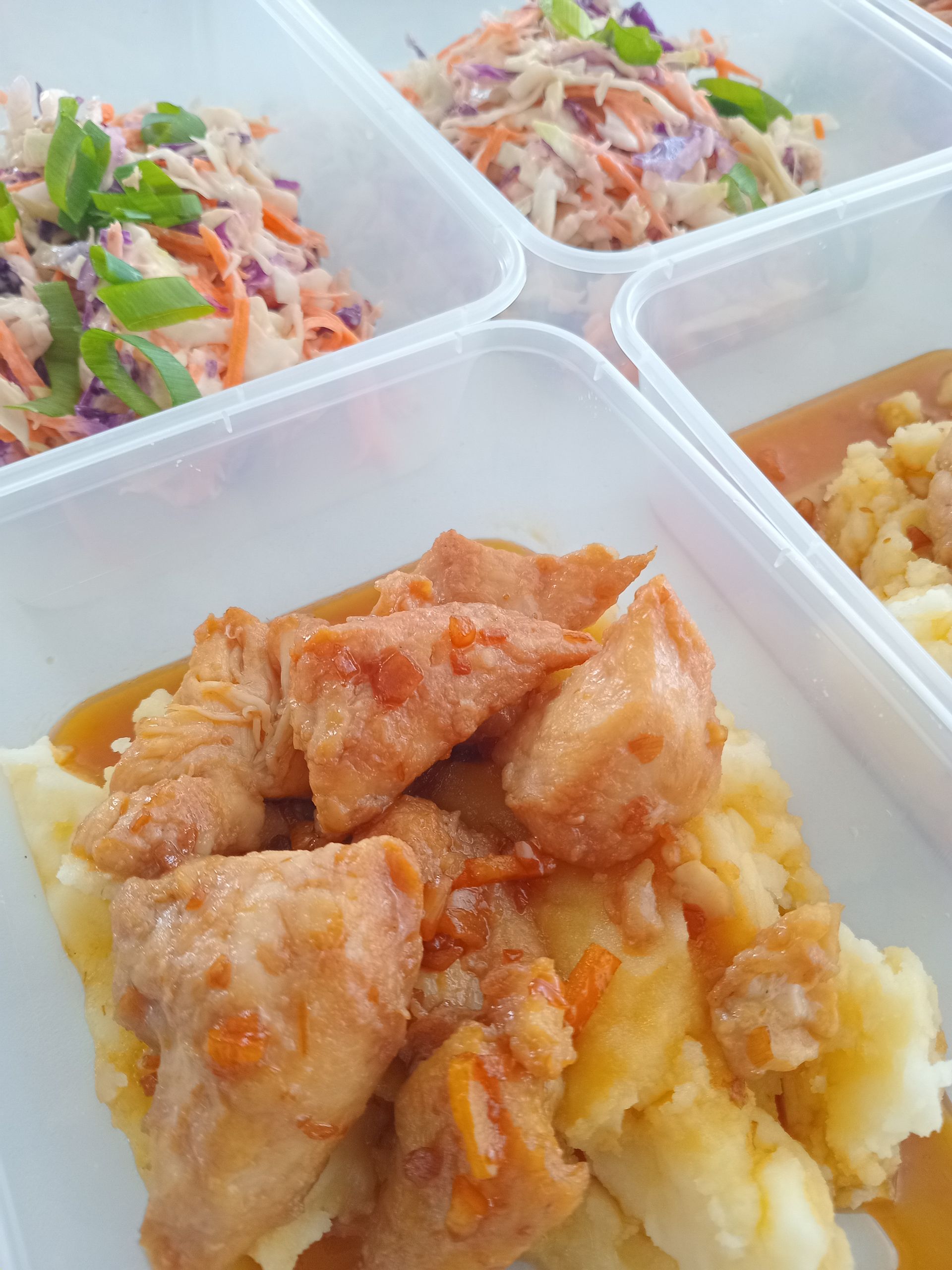 Meal prep containers with chicken and mashed potatoes, and coleslaw.