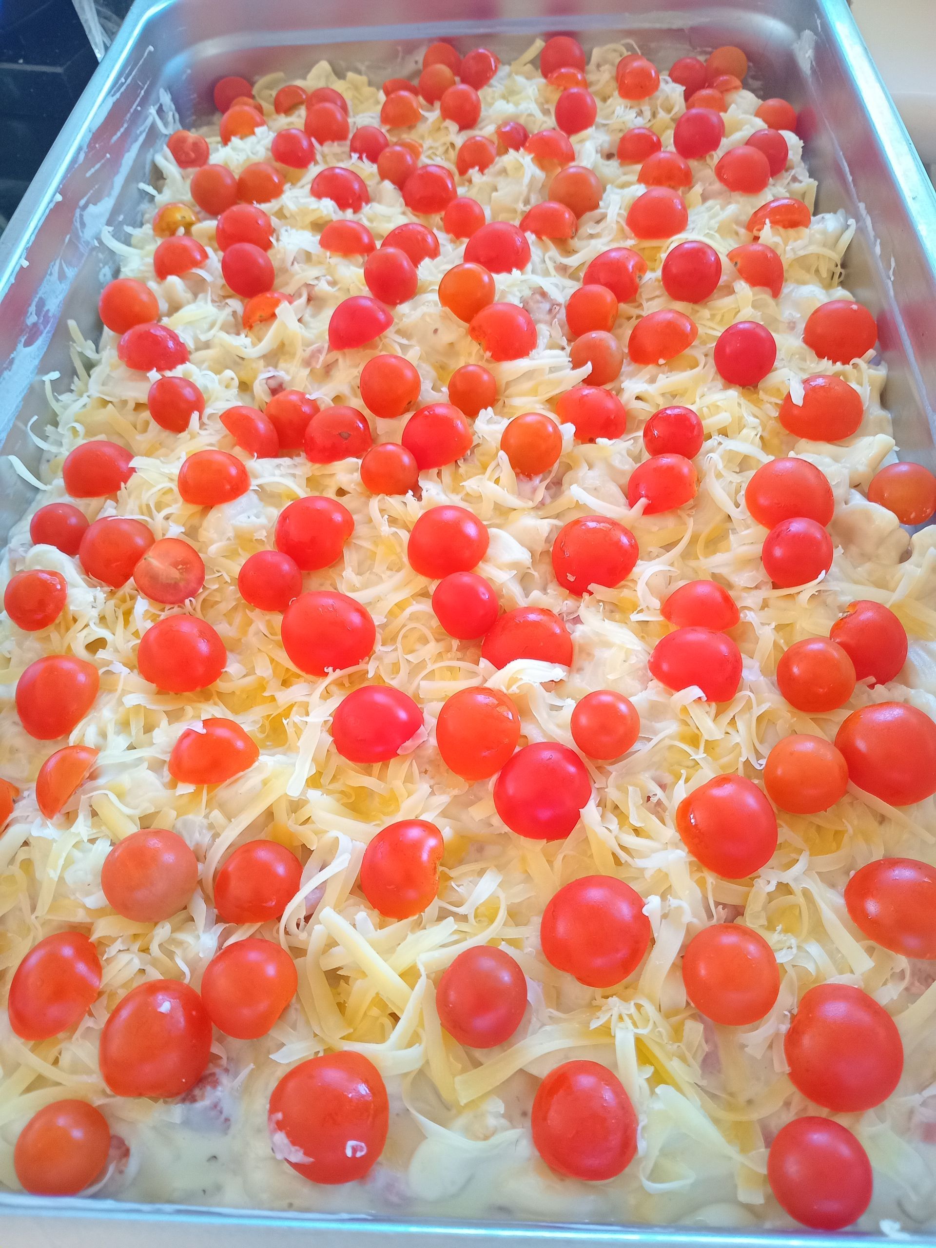 Casserole dish topped with cherry tomatoes and shredded cheese.