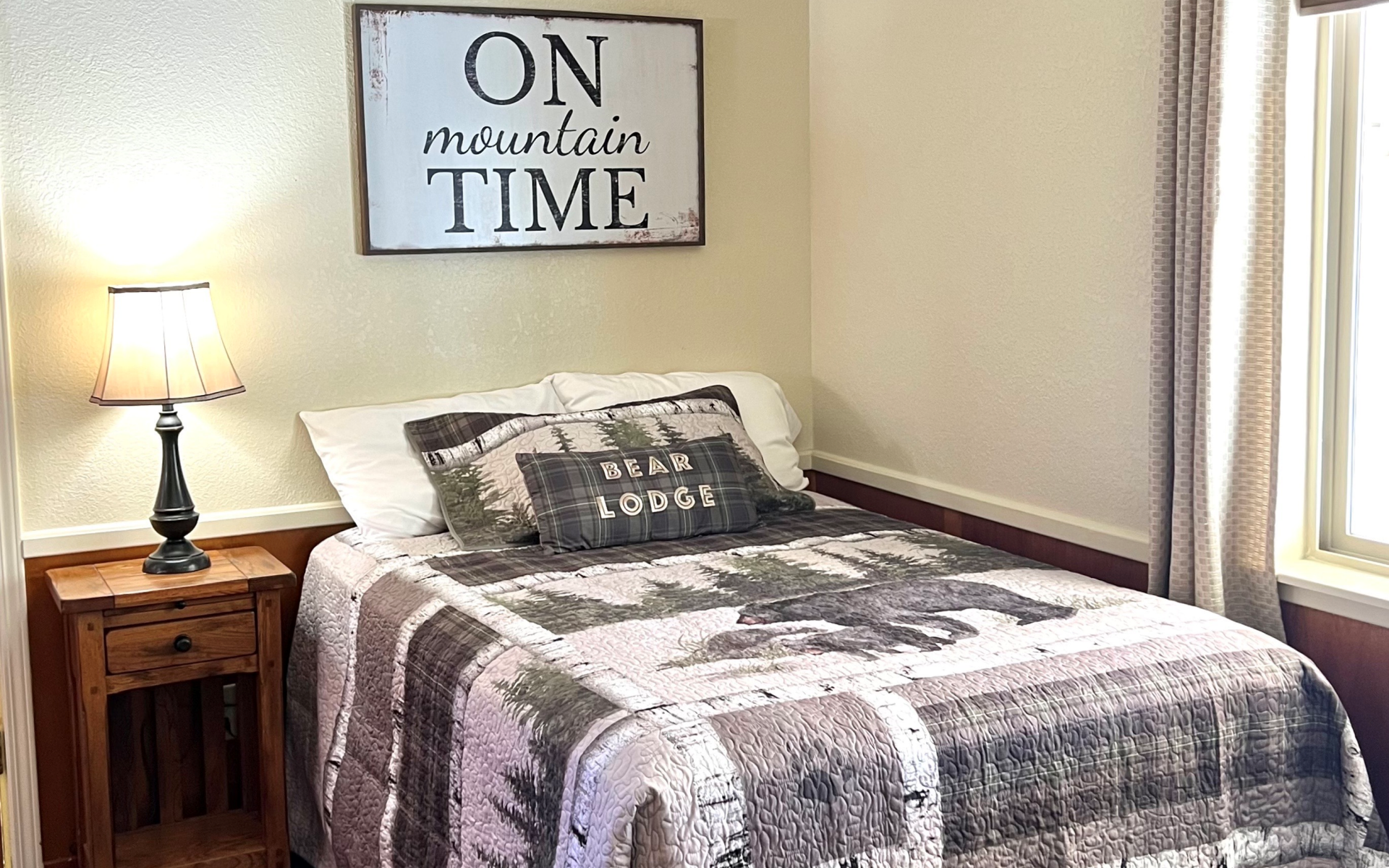 There is a sign on the wall above the bed that says `` on mountain time ''.