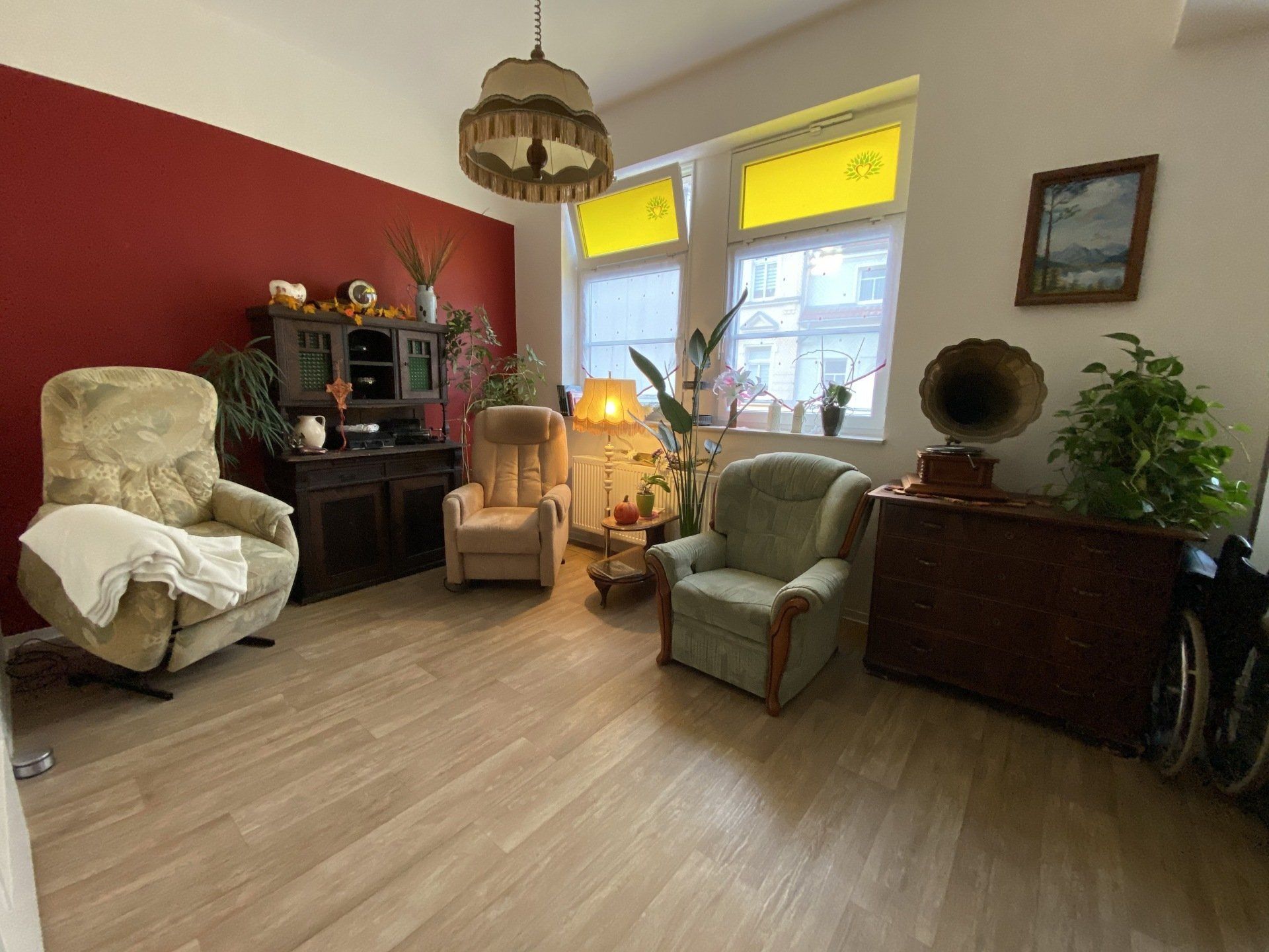 Gemütliches Wohnzimmer mit Vintage-Möbeln, darunter Sessel, ein Grammophon und eine rote Akzentwand.