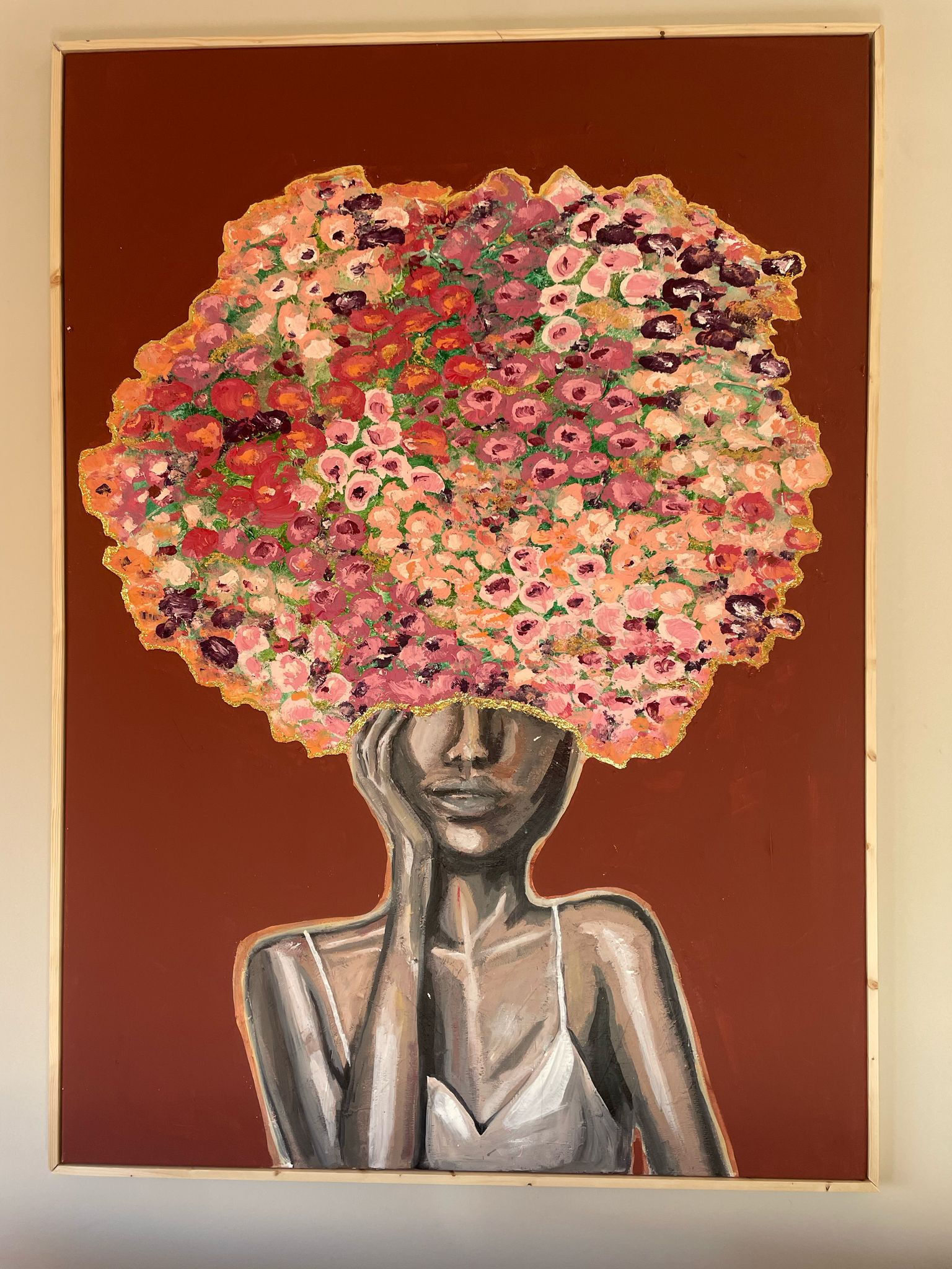 Aan de muur boven de bank hangt een schilderij van een vrouw met bloemen in haar haar. bordeaux en goud