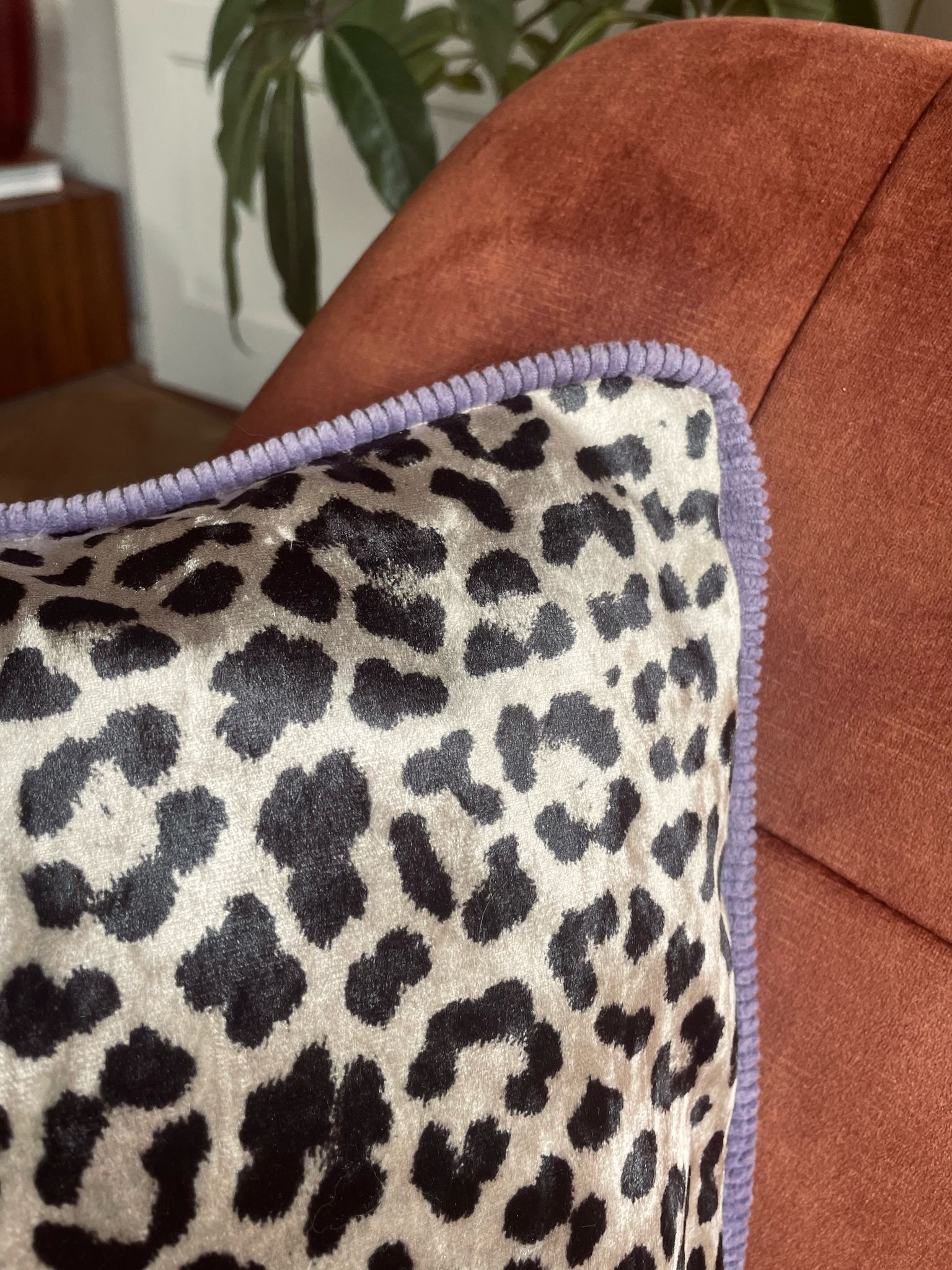 Op een bruine bank ligt een kussen met luipaardprint.