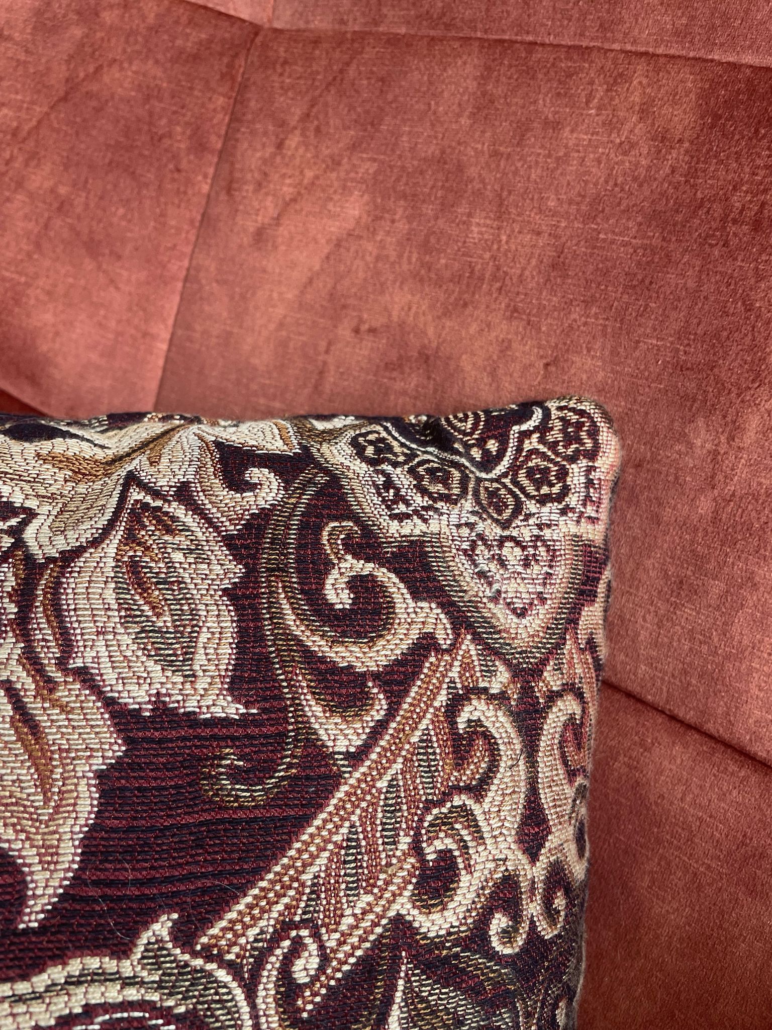 Een bordeaux kussen ligt op een rode bank.