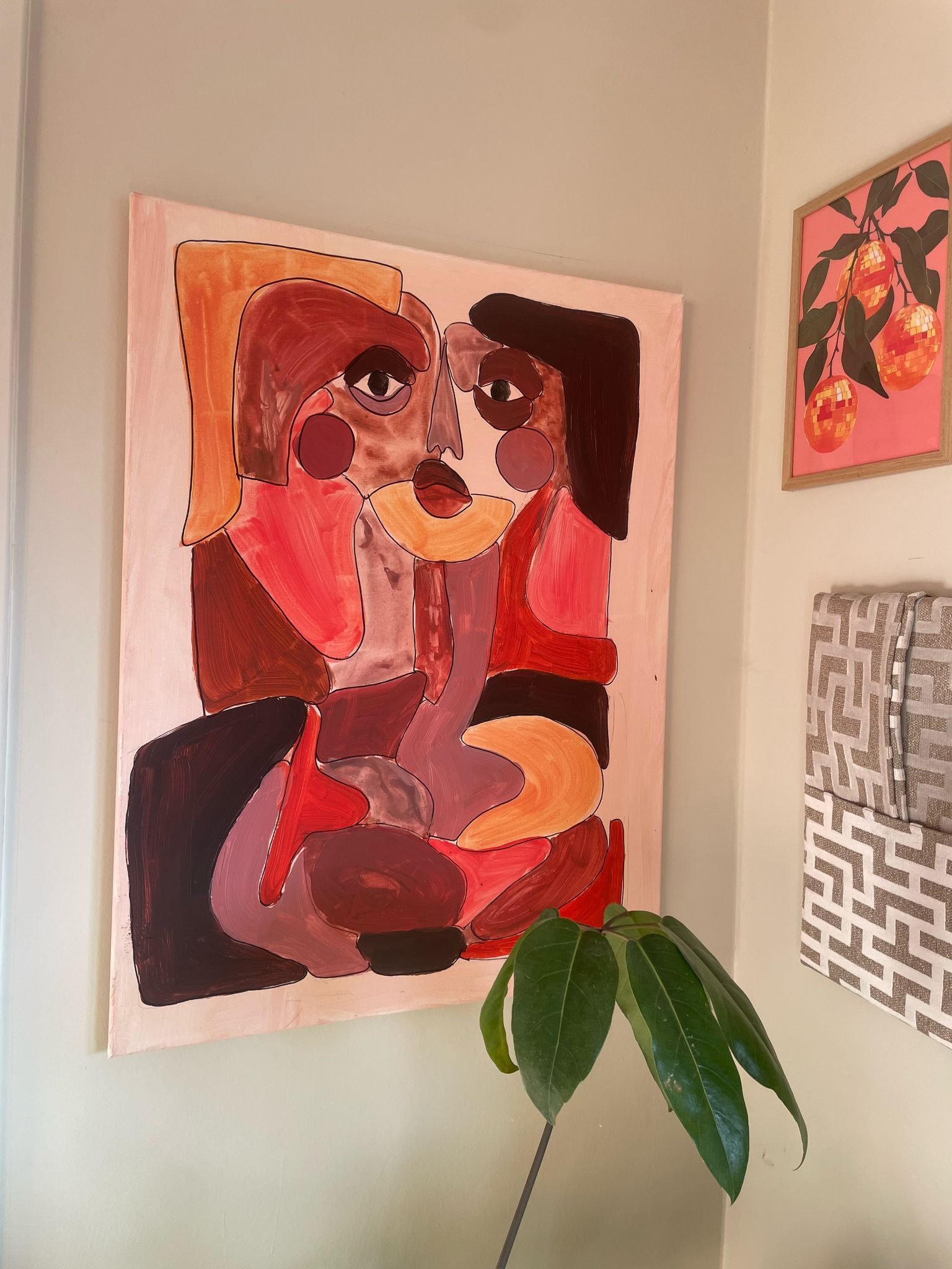 Een schilderij in natuur en bordeaux tinten van een abstract gezicht voor aan de muur in een stijlvol interieur