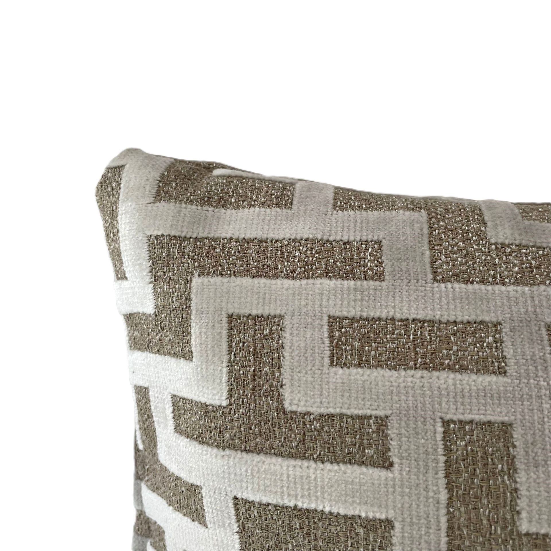 Rechthoekig decoratief kussen met geometrisch patroon in beige en crèmekleur.