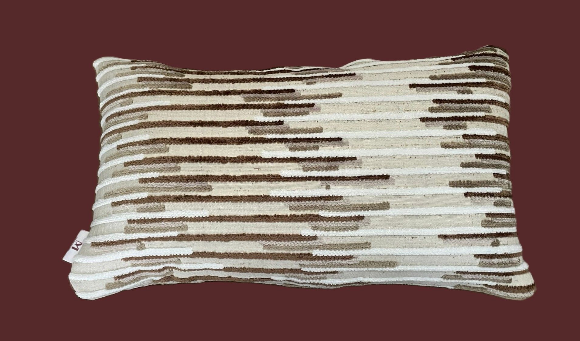 Beige en bruin gestreept kussen met textuur op een bruine achtergrond.