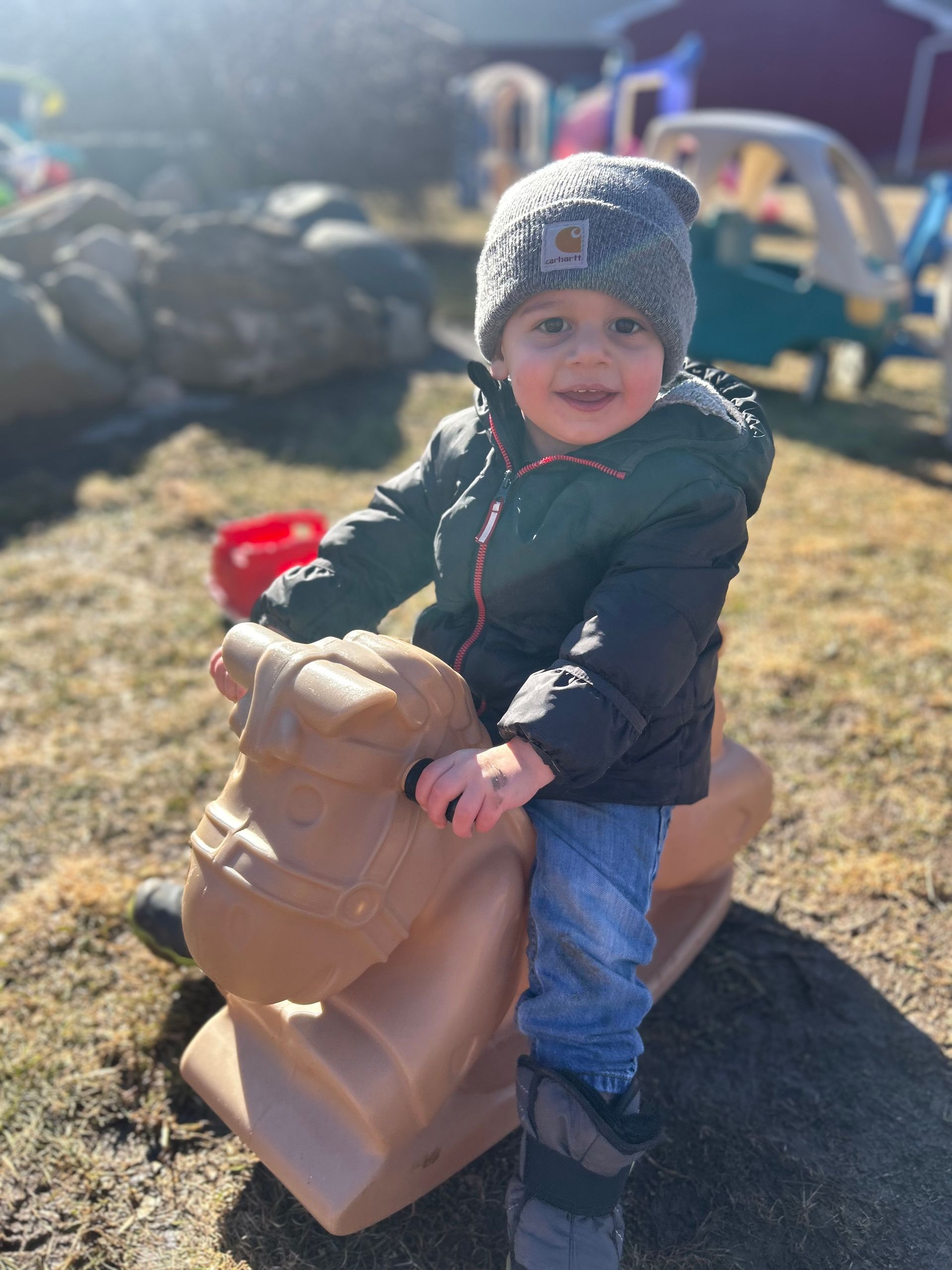 A little boy is sitting on a rocking horse.