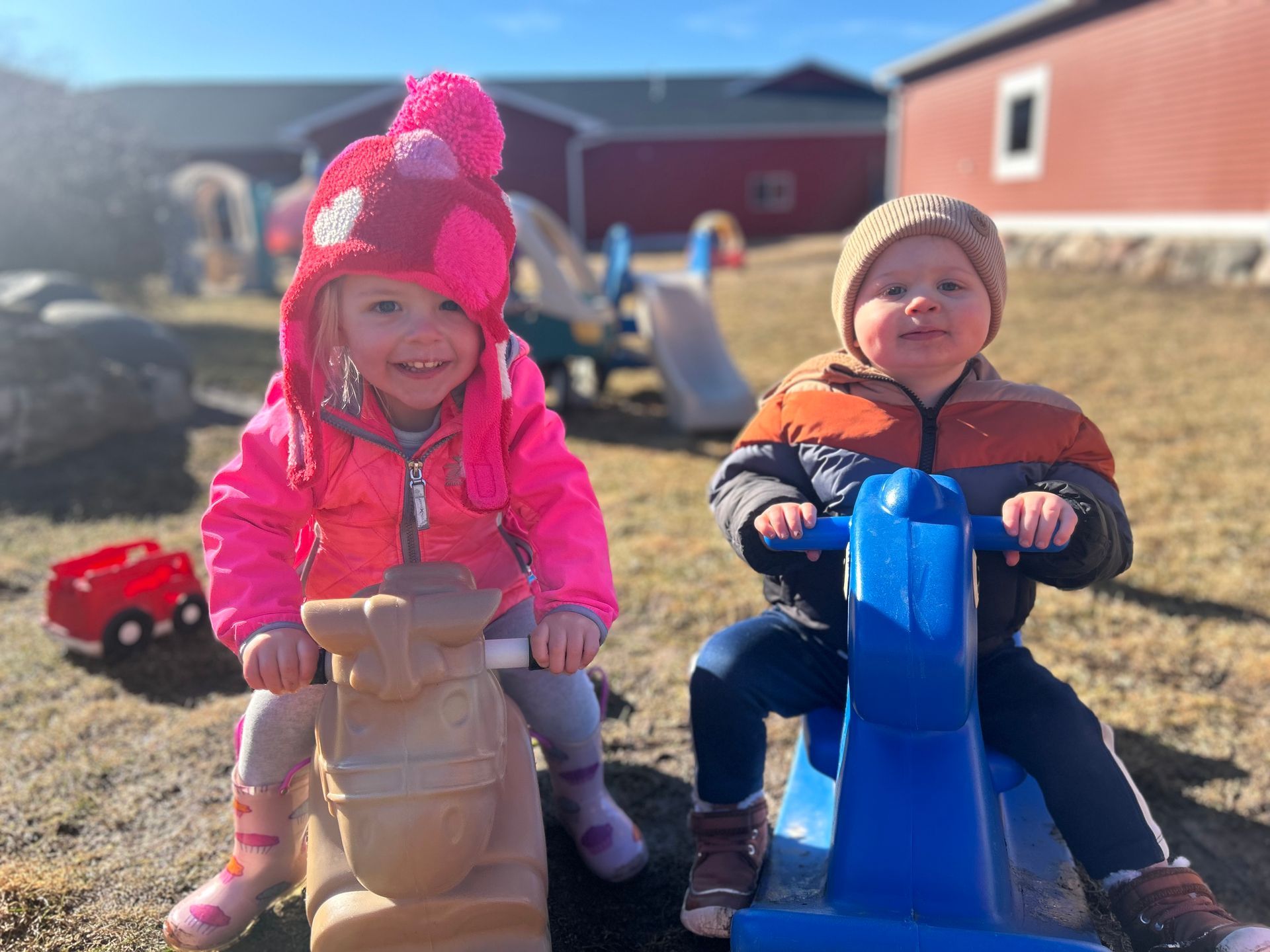 A boy and a girl are sitting on a rocking horse.