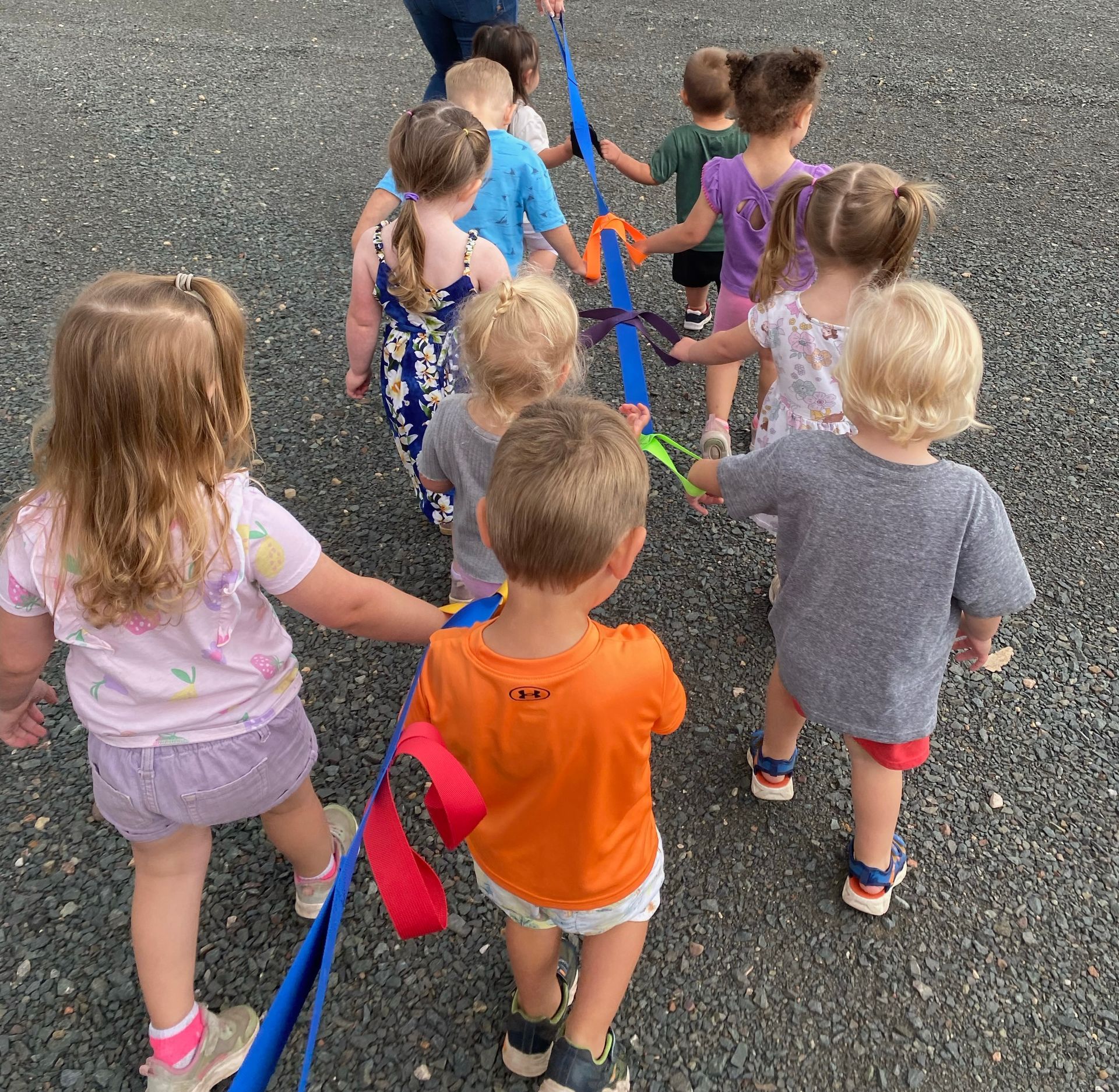 A group of children are walking down a gravel road holding hands