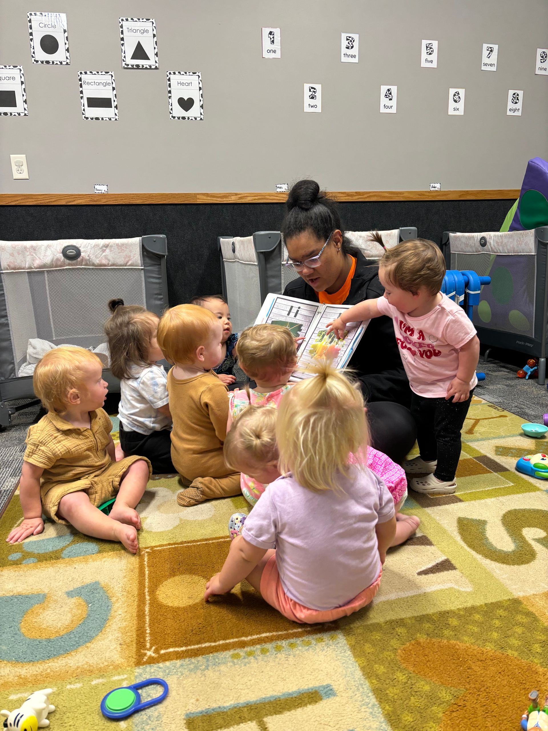 A woman is reading a book to a group of babies.