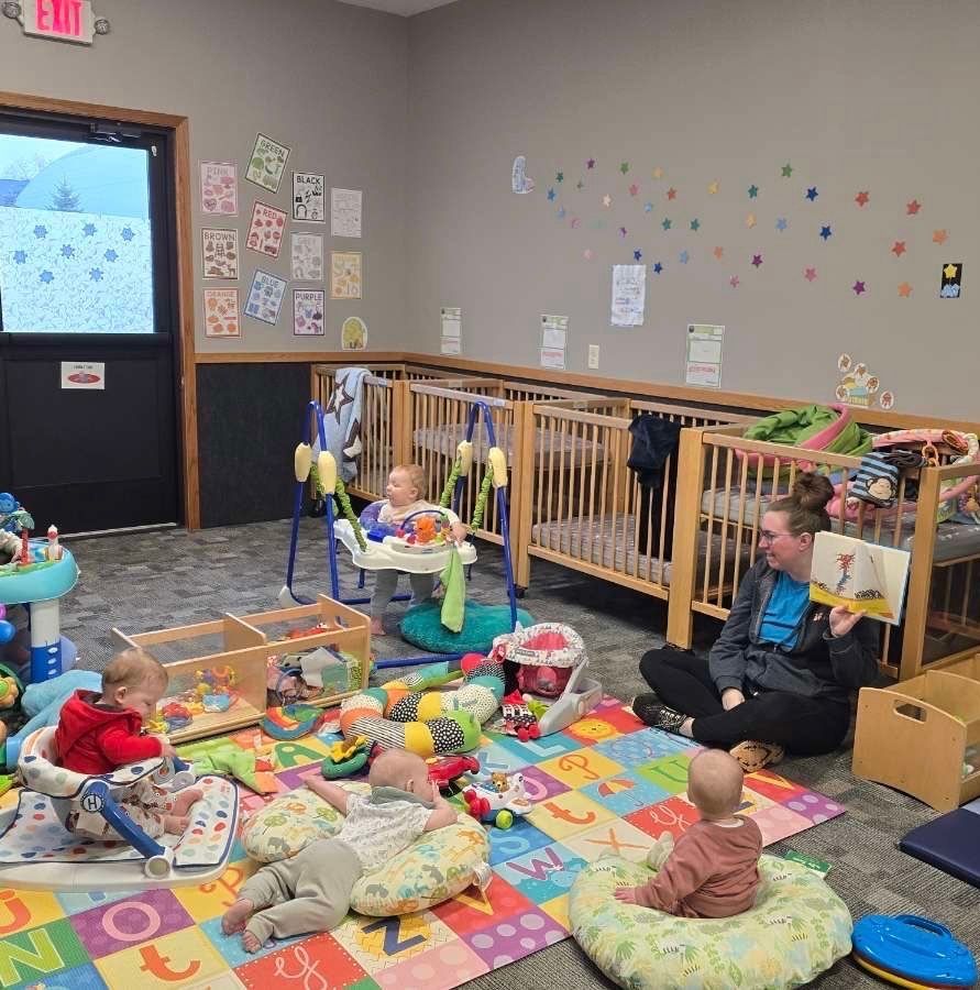 A group of babies are playing in a room with cribs and toys.