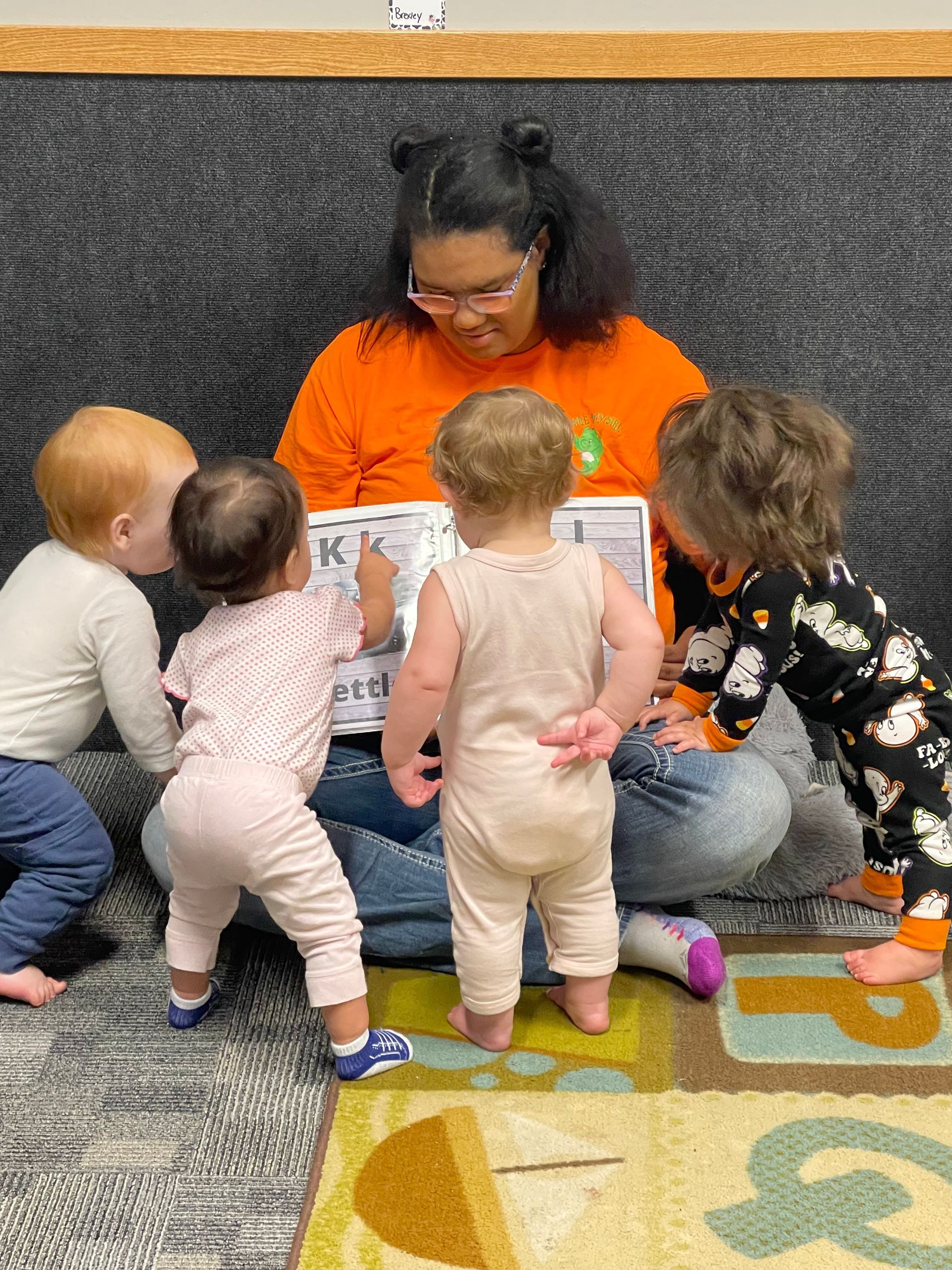 A woman is reading a book to a group of babies.