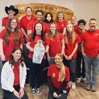 A group of people in red shirts are posing for a picture.