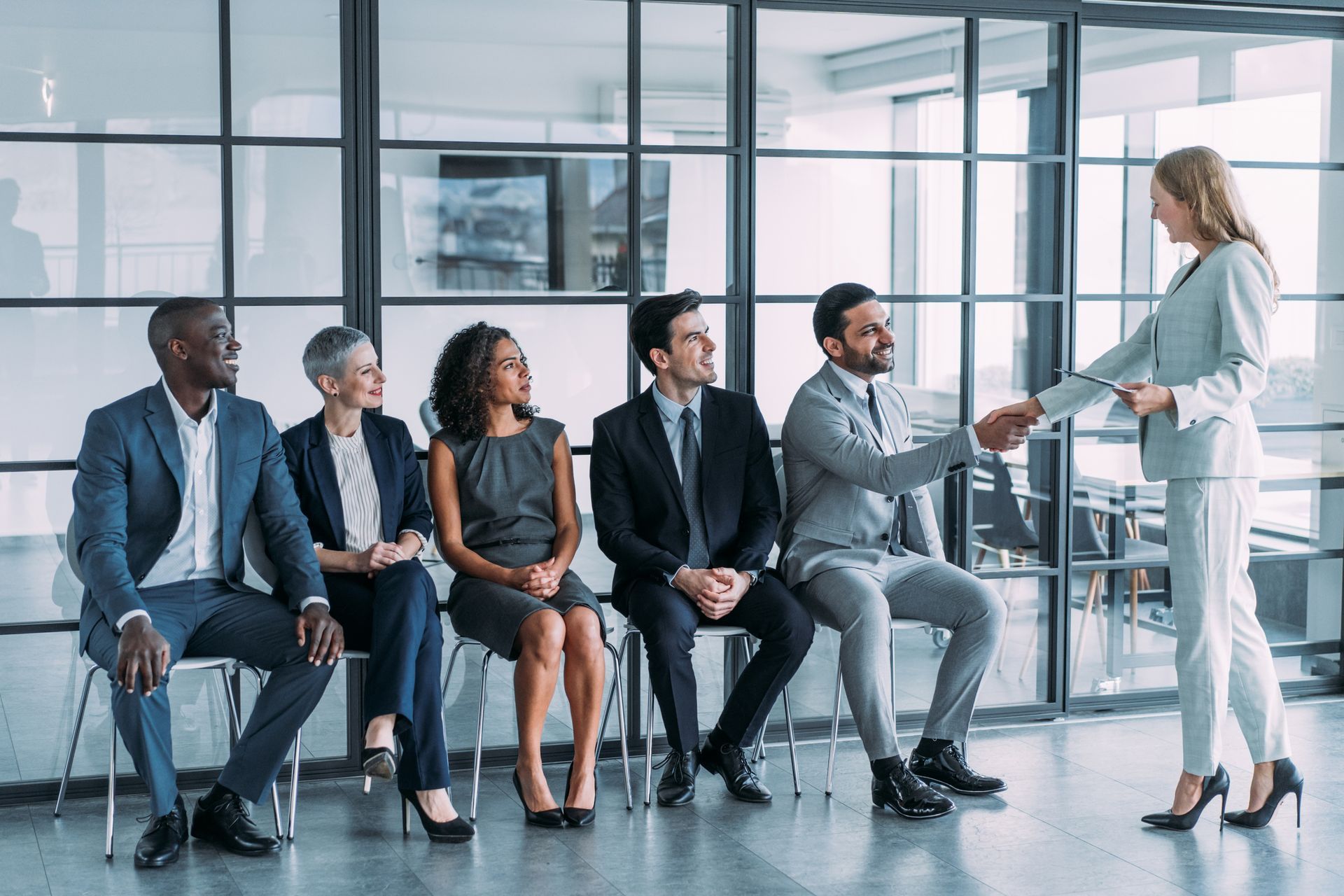 A Woman is Shaking Hands With a Group of People Sitting in Chairs