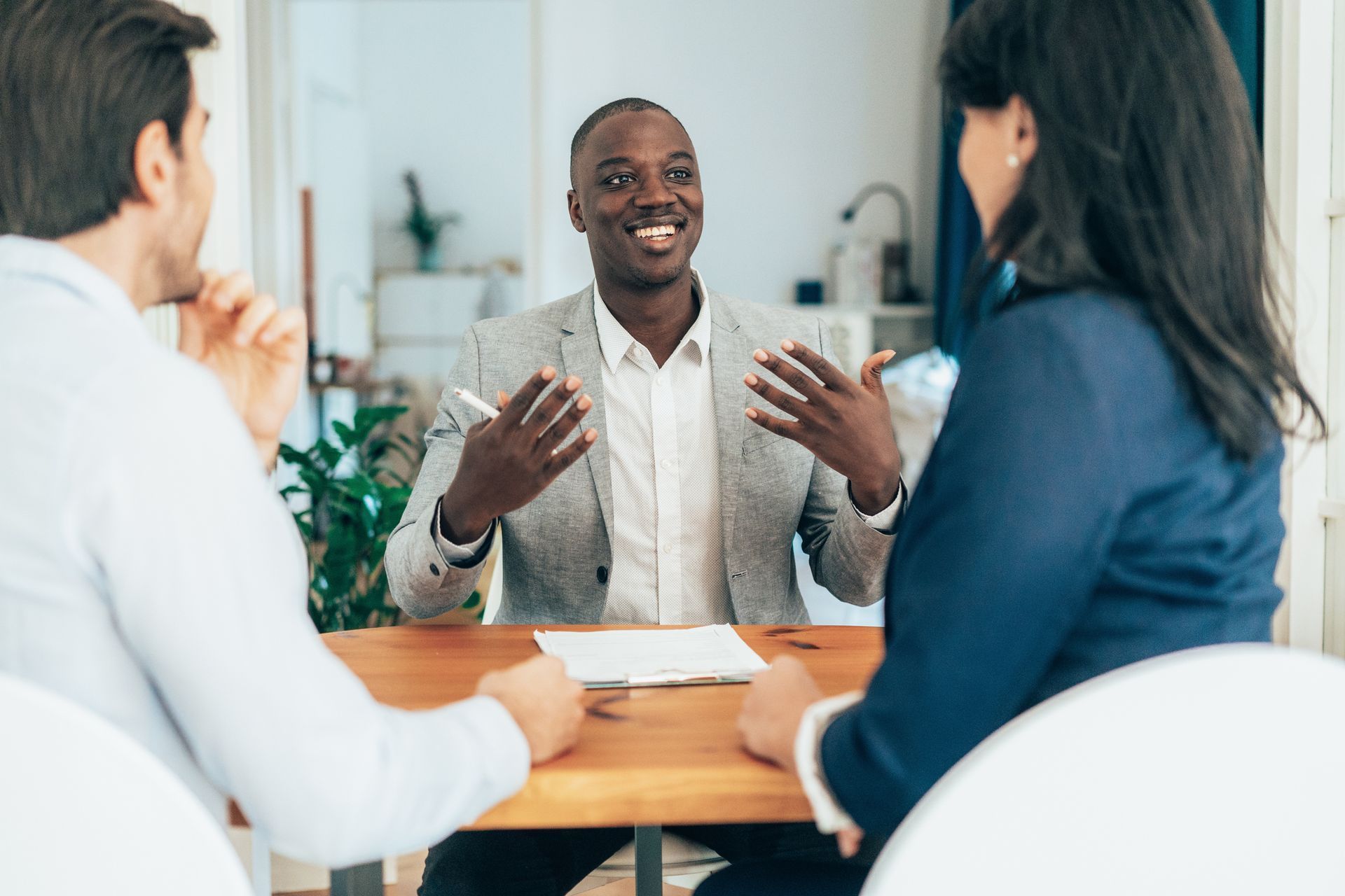 A Man is Sitting at a Table Talking to Two People