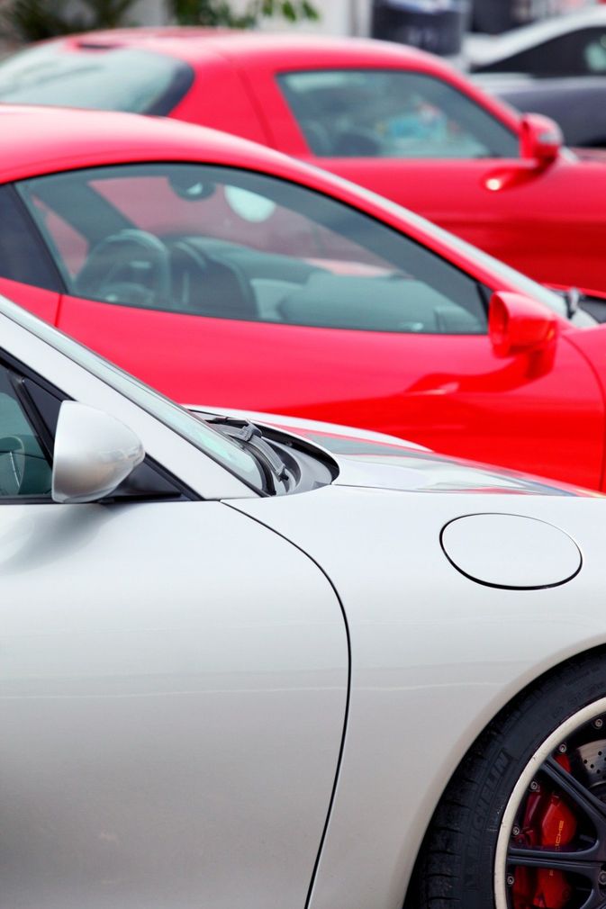 A white car is parked next to a red car