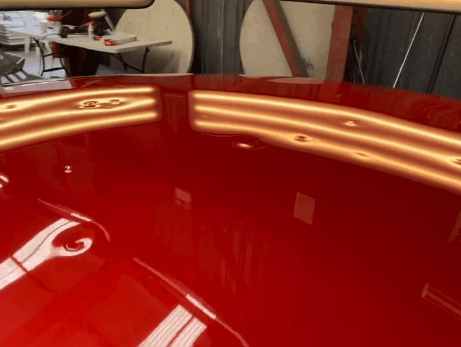 A close up of a red car with dents on the bonnet