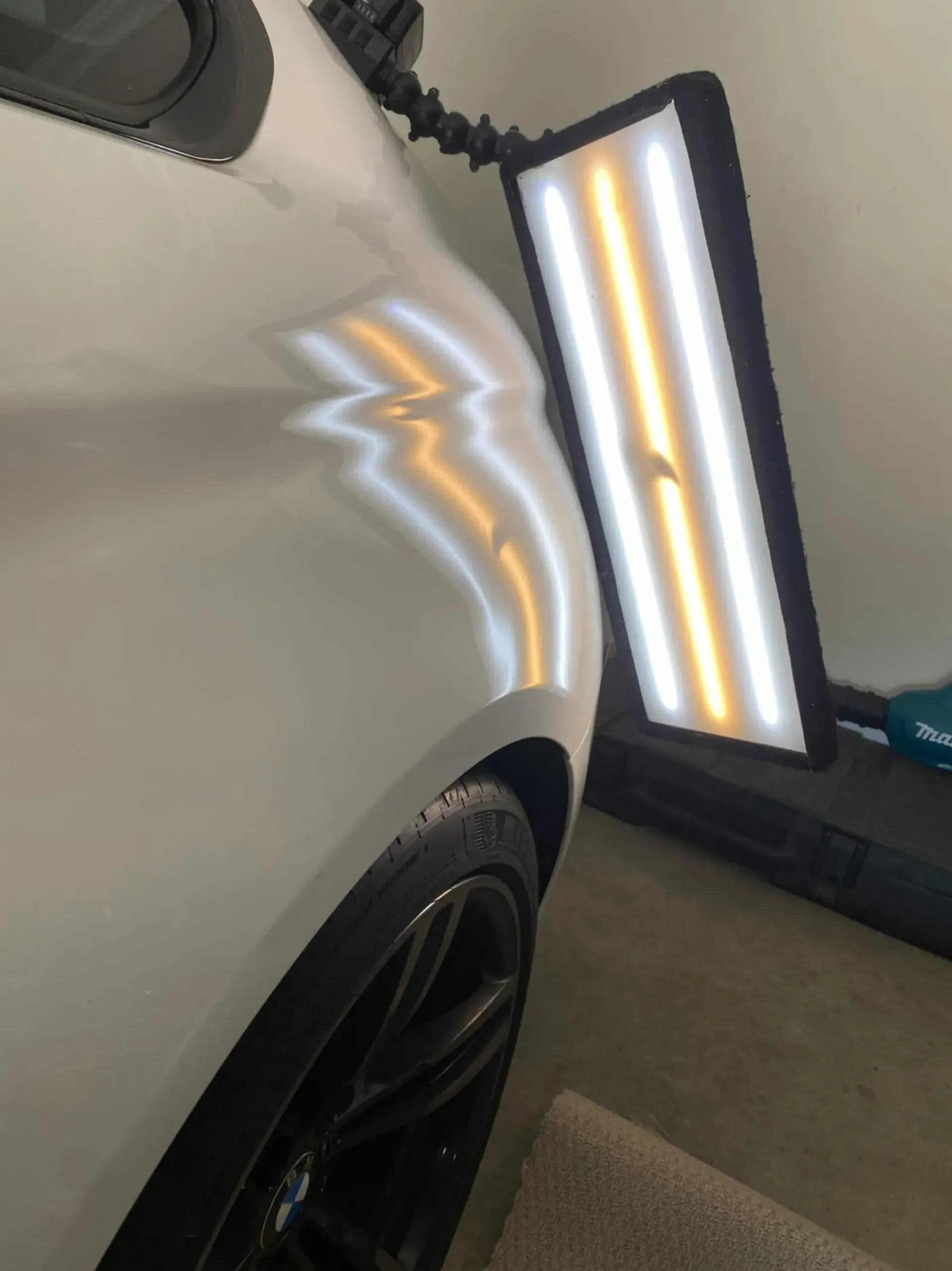 A white car with a light on the side of it to see no more dents.