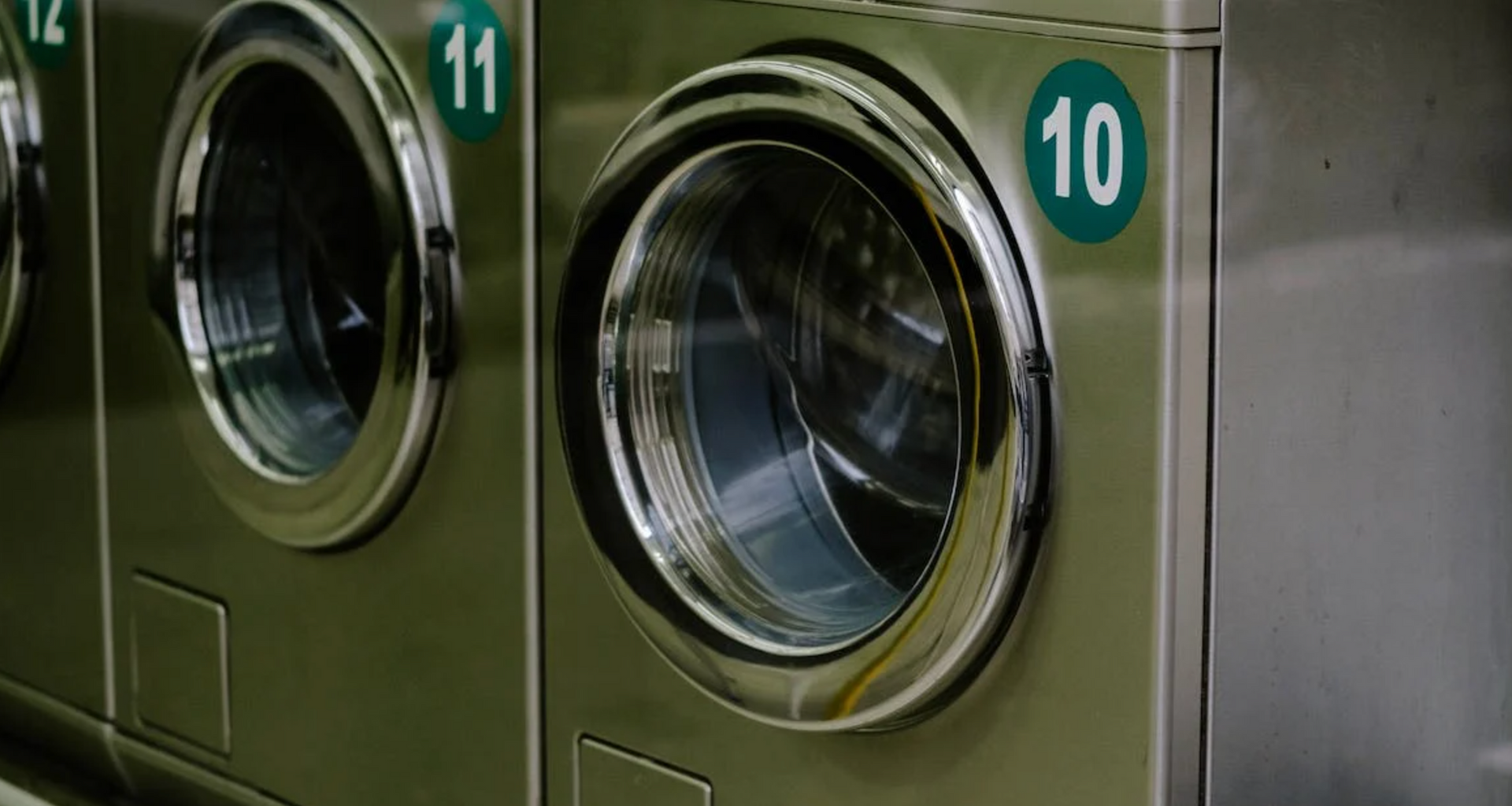 A row of washing machines are lined up in a laundromat.