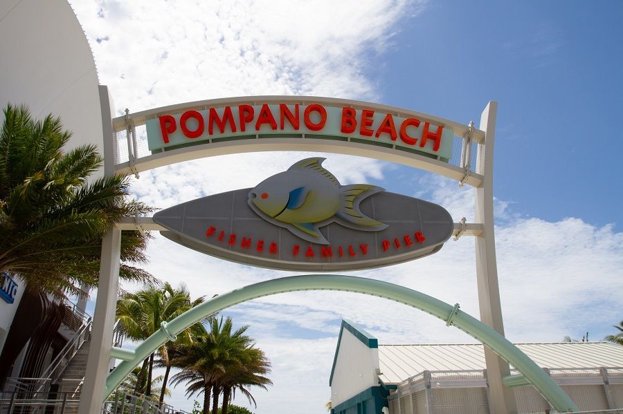 Pompano Beach entrance arch with colorful fish logo and palm trees under a clear sky