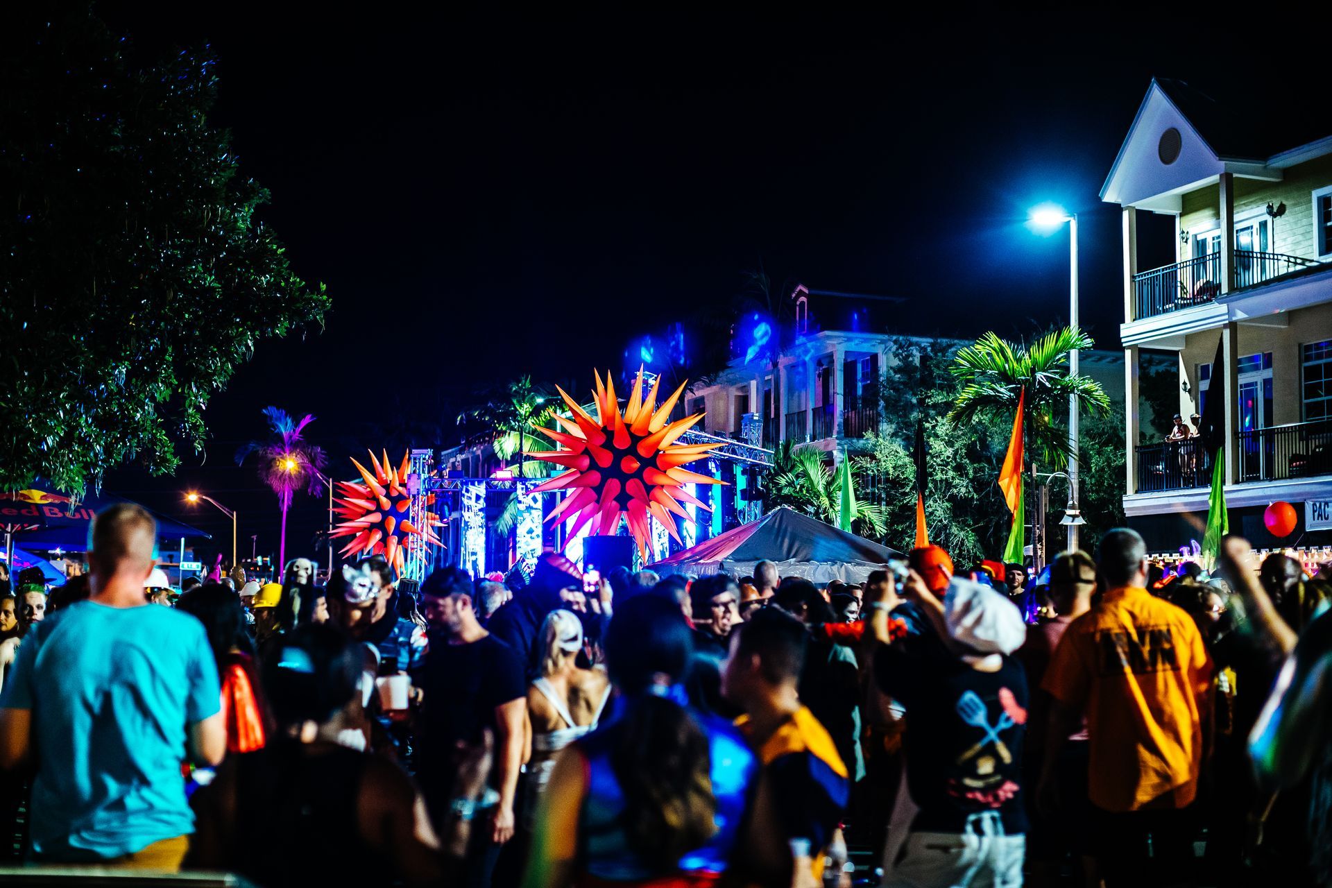 Crowd at a nighttime street festival with bright neon decorations and a lit parade float Wilton Manors