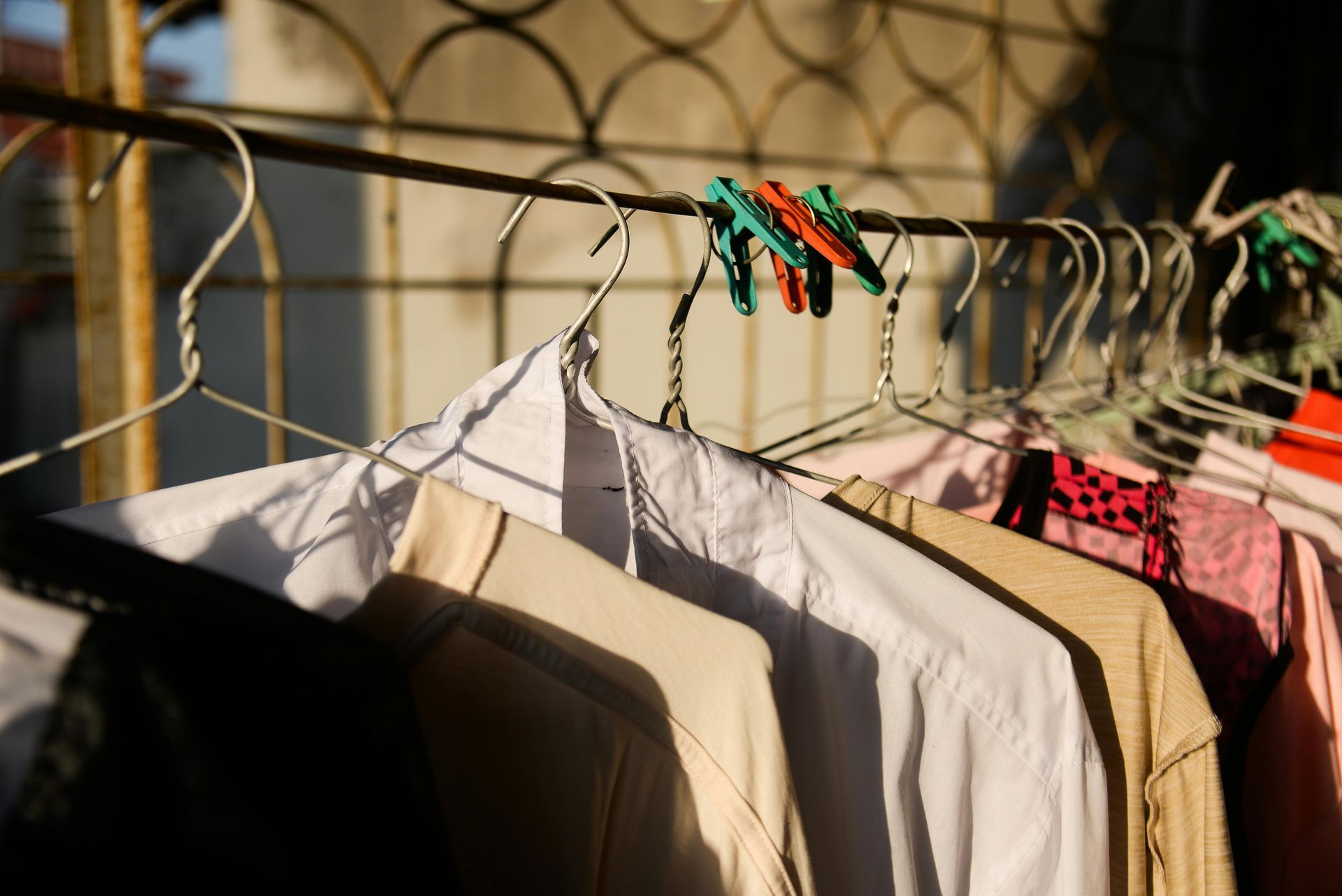 Clothes hanging on a wire rack with colorful clothespins in warm sunlight