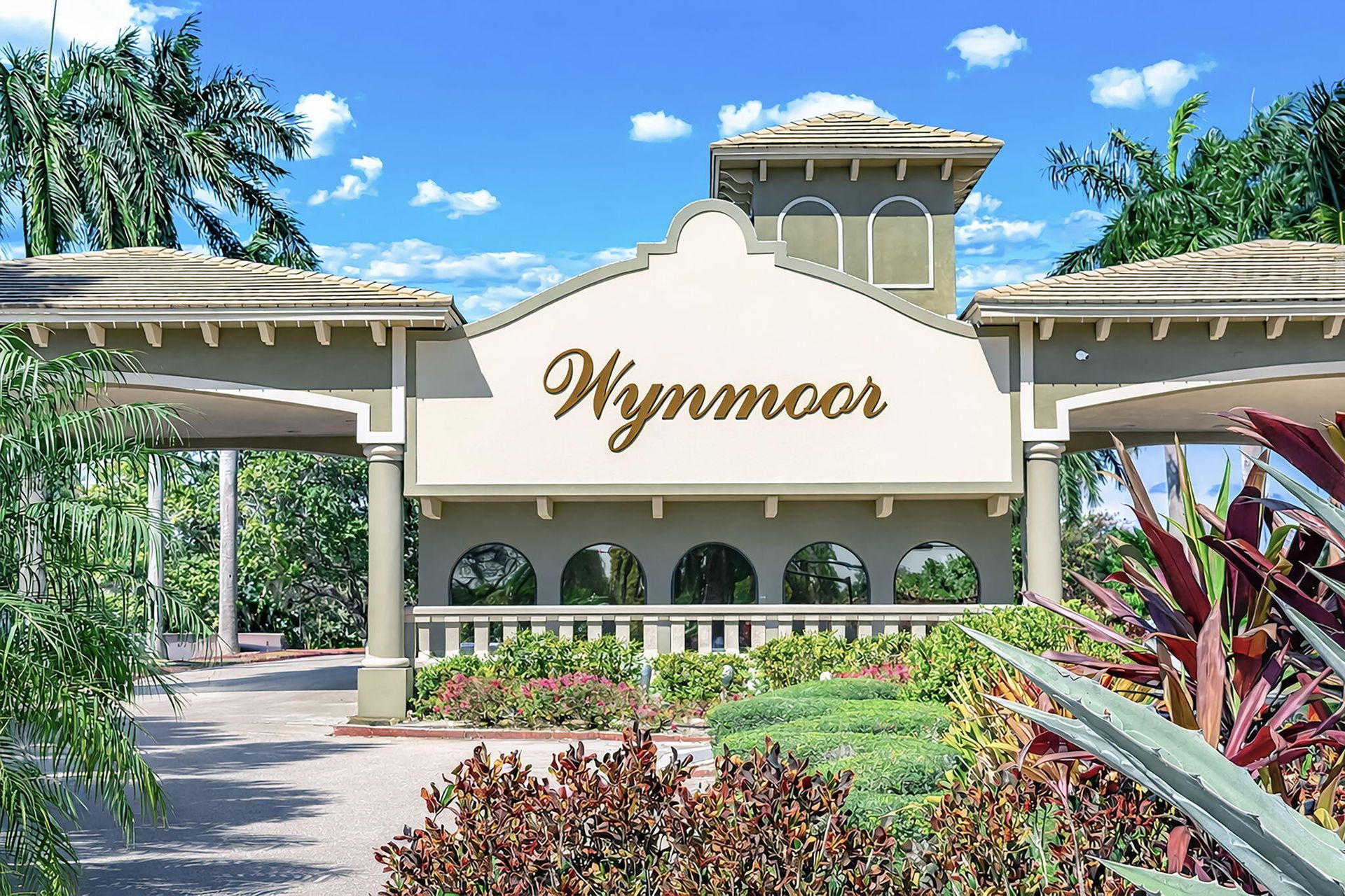 Wynnmoor entrance sign under a tropical blue sky with palms and landscaped greenery