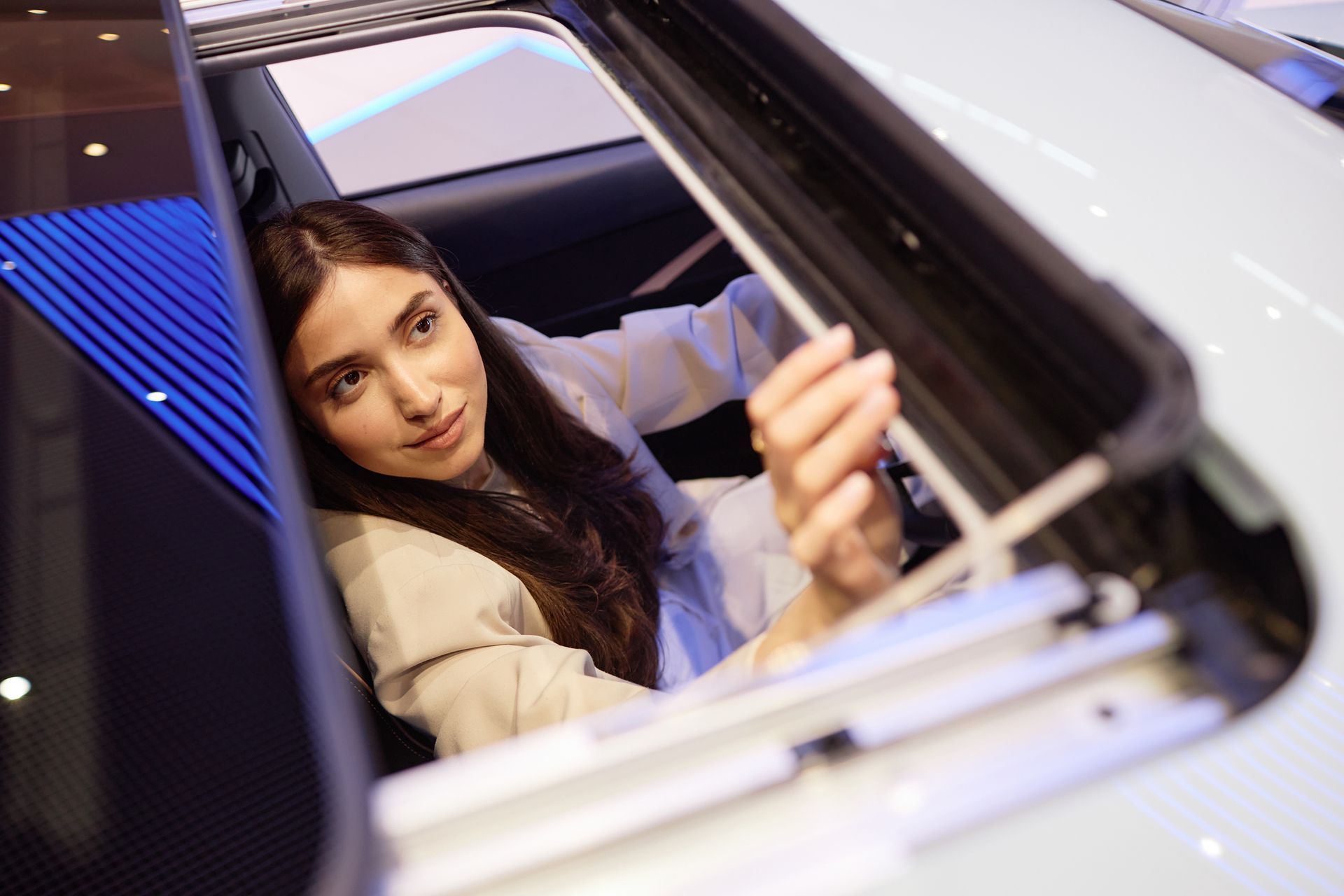 Shot through the opened car sunroof of a young woman inspecting interior details. Shot through the opened car sunroof of a young woman inspecting interior details.