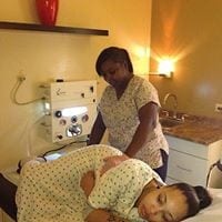 A nurse is giving a pregnant woman a massage in a hospital room.