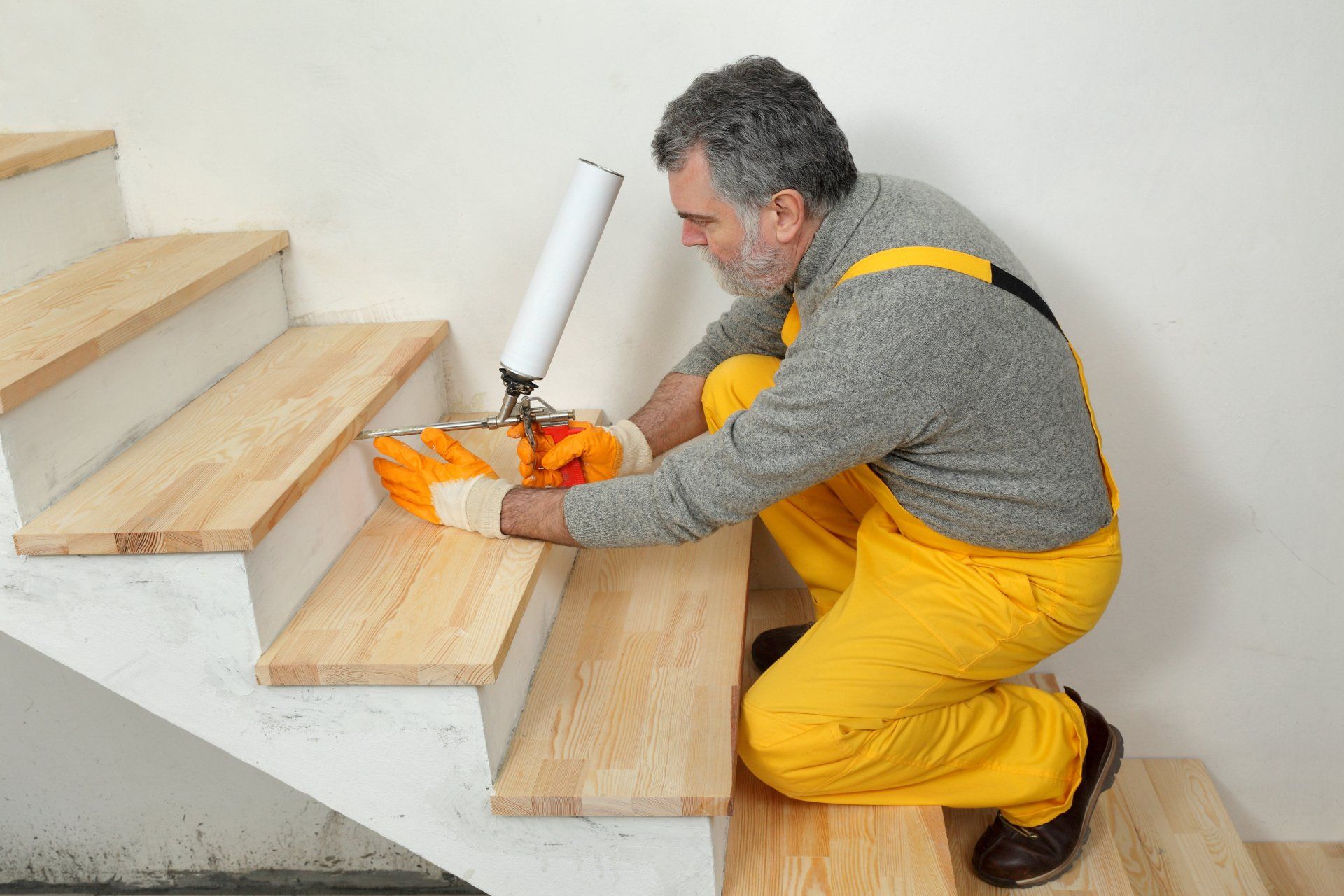 A man is installing wooden steps on a set of stairs.