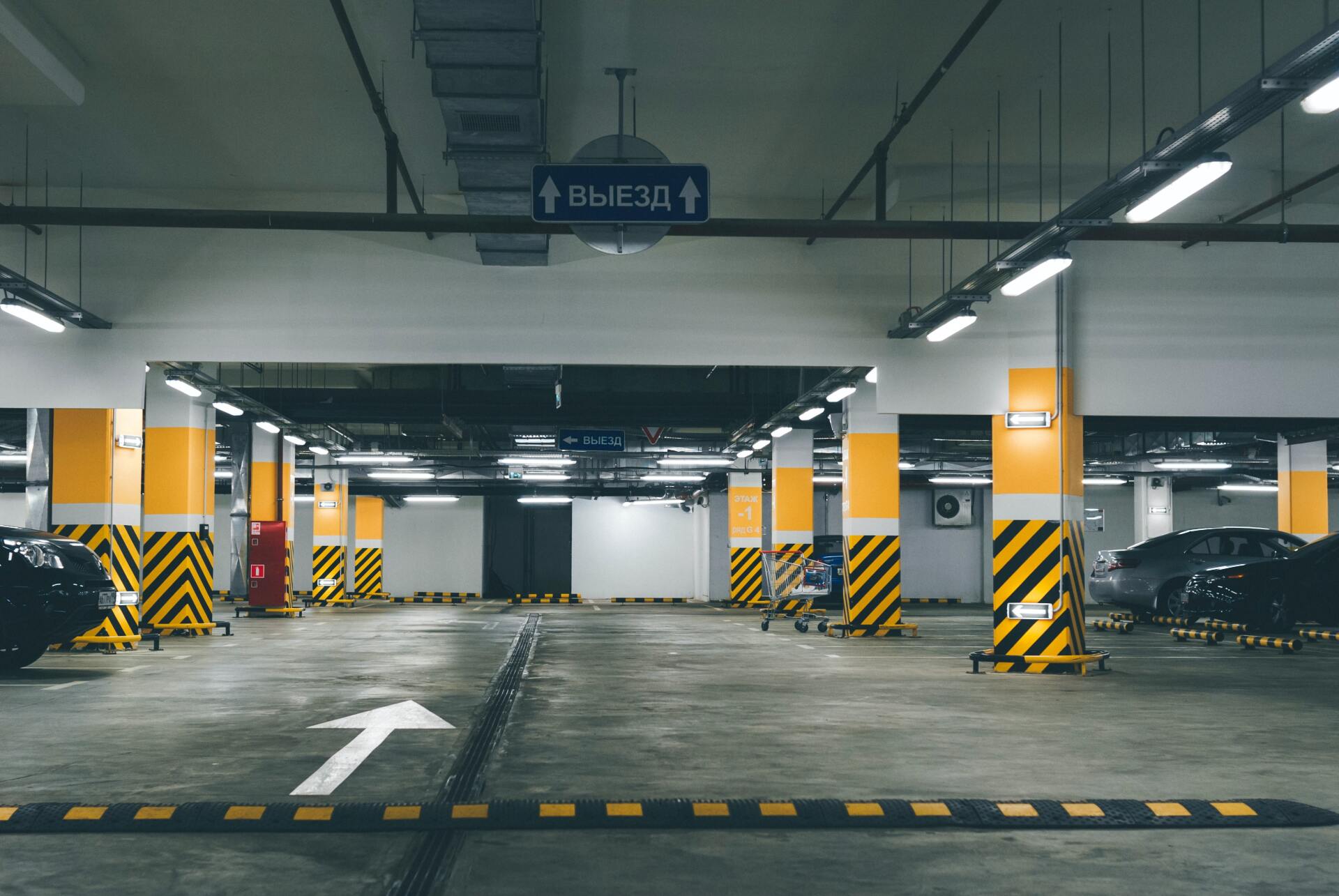 A parking garage with cars parked in it and an arrow pointing to the right.