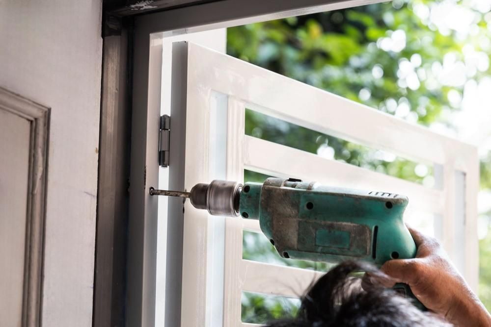 A man is using a drill to drill a hole in a door.