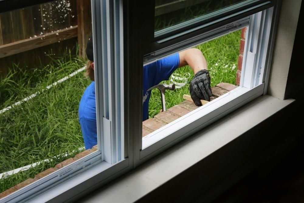 A man is installing a window in a house.