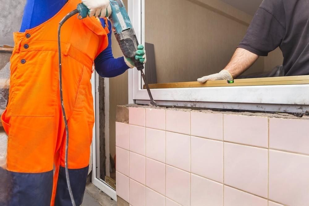 A man is using a hammer to drill a hole in a wall.