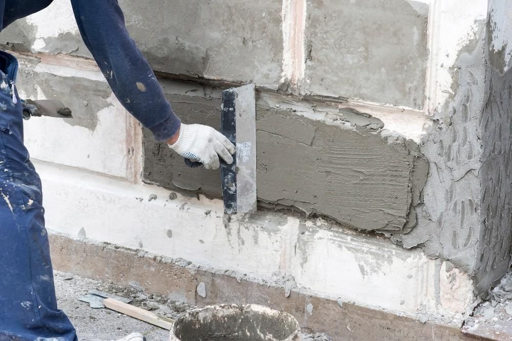 A man is plastering a wall with a trowel.