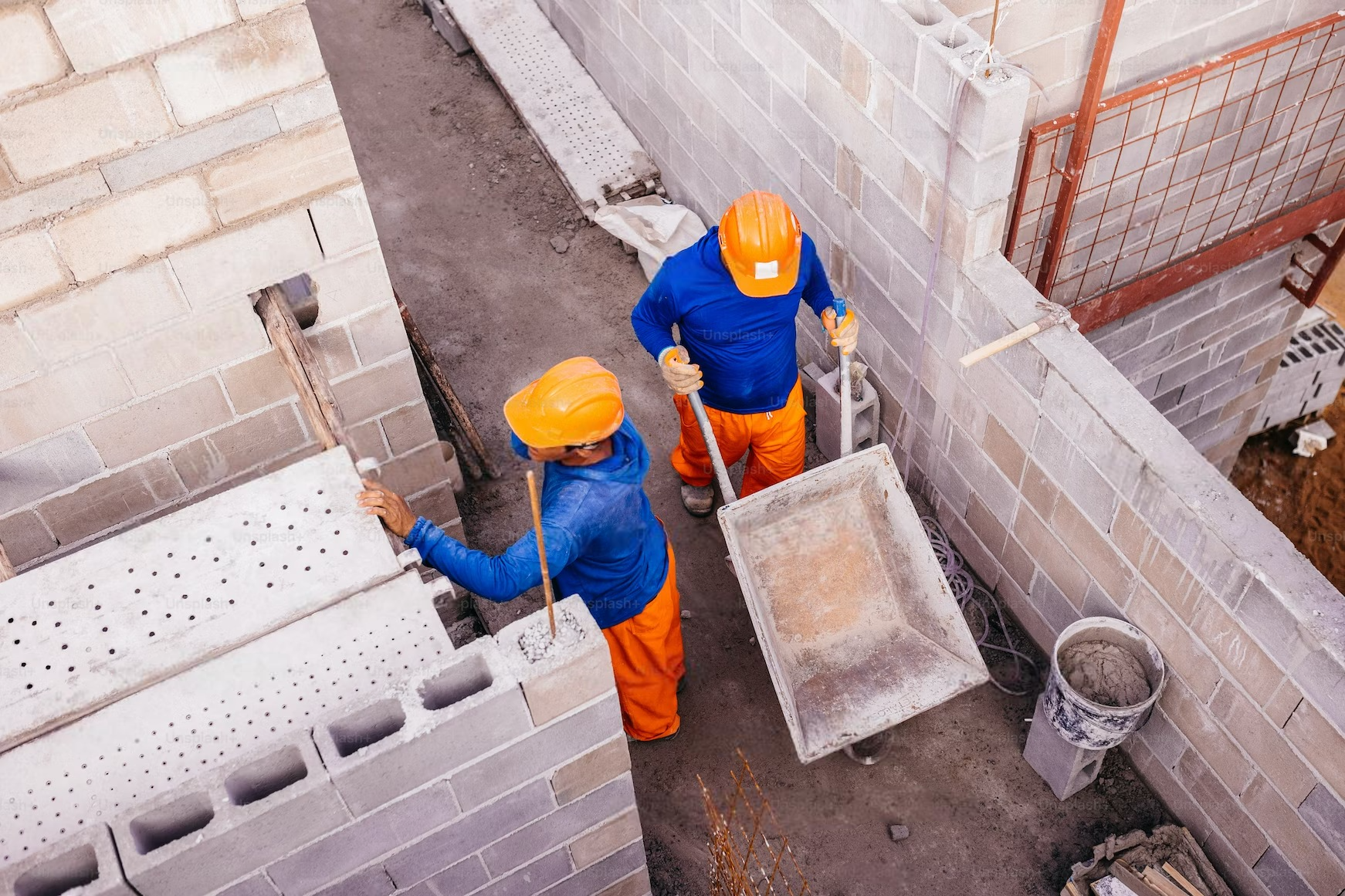 Two construction workers are working on a brick wall.
