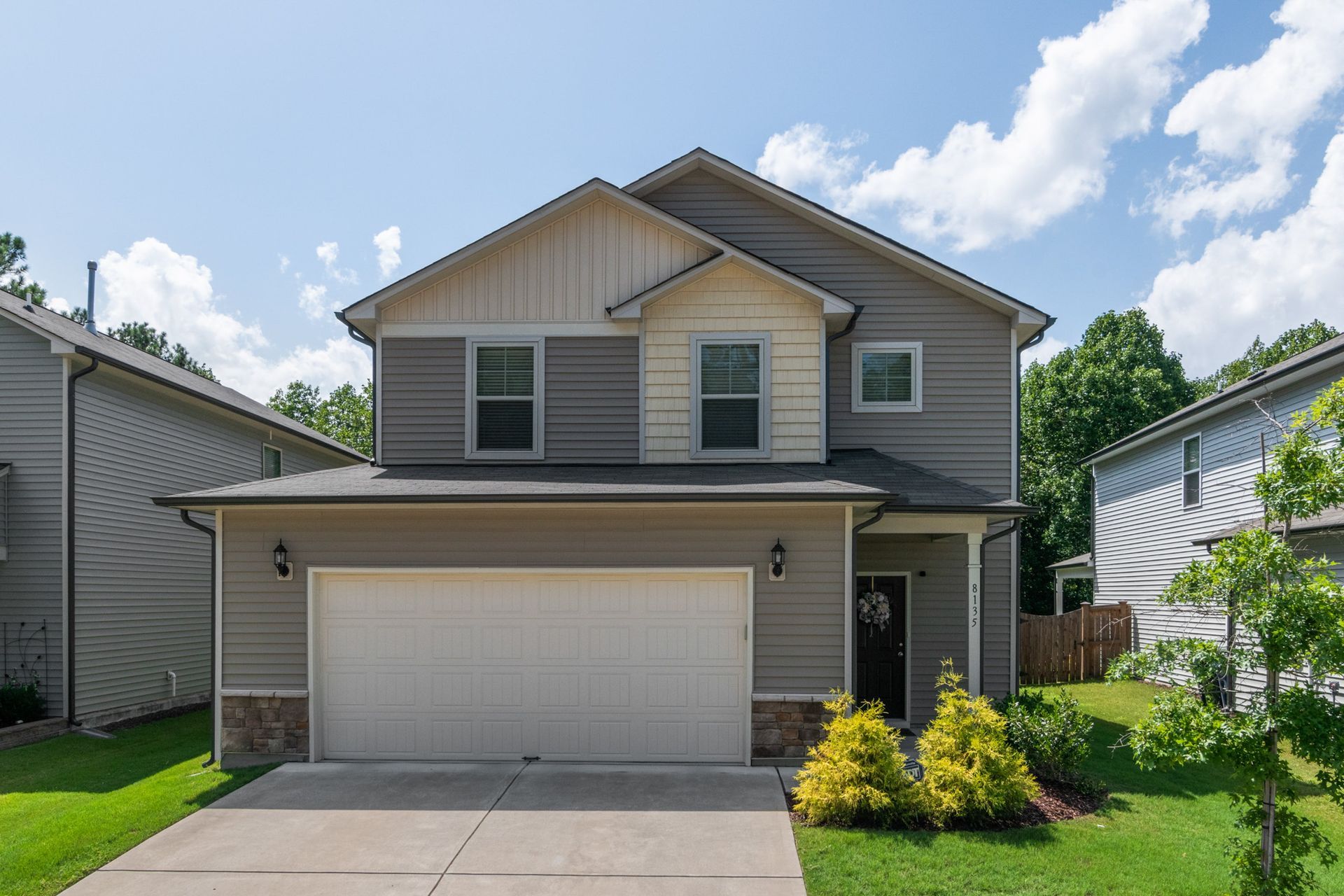 A large gray house with a white garage door is for sale.