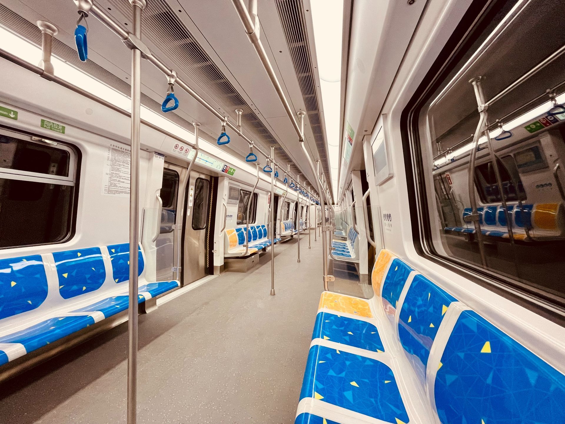 The inside of an empty subway car with blue seats.