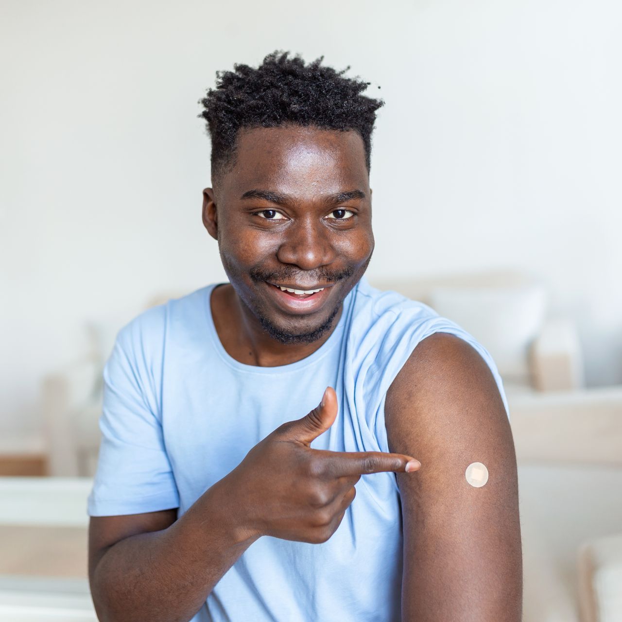 a man is pointing at his arm after getting a vaccine .