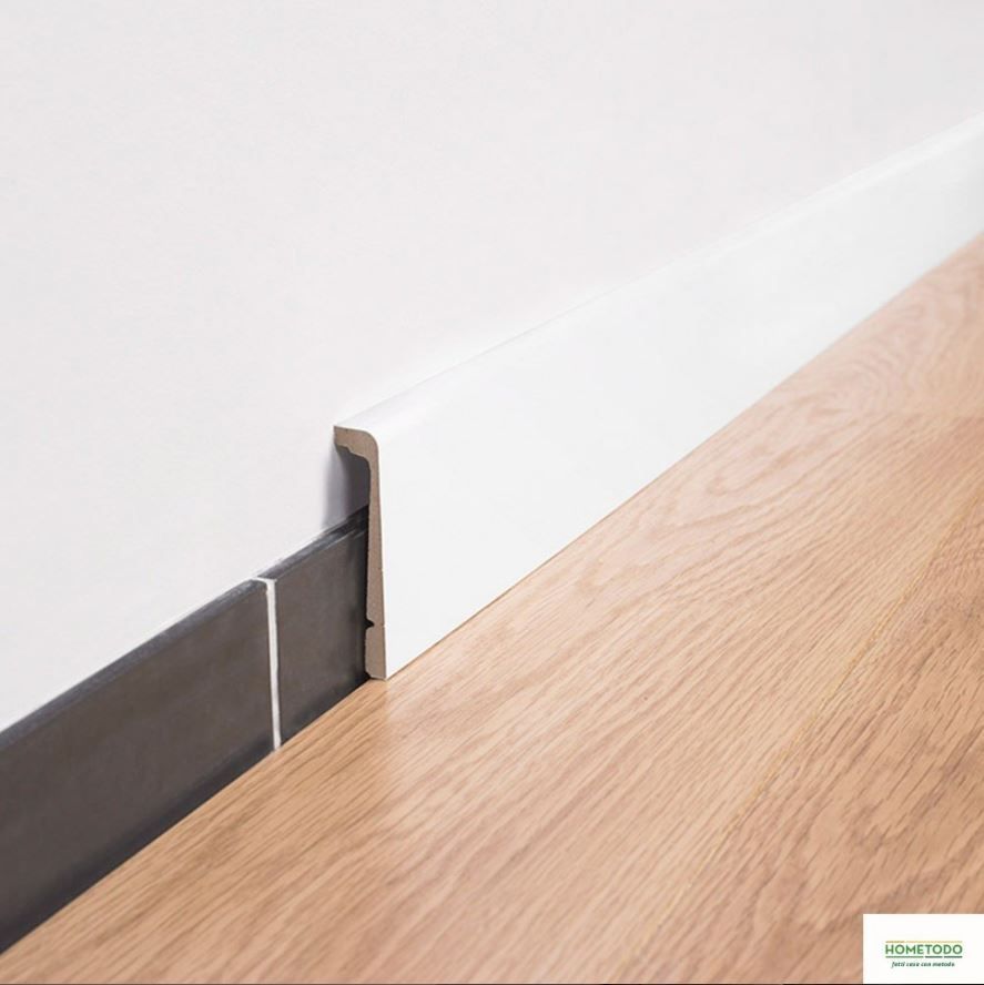 Un pavimento in legno con un battiscopa bianco