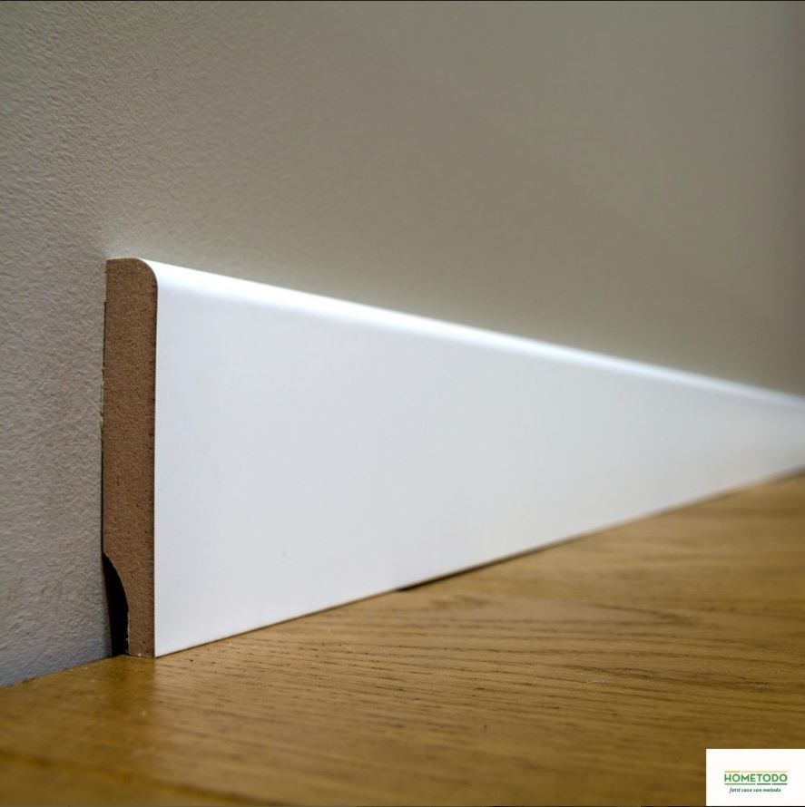 Un battiscopa bianco è appoggiato su un pavimento in legno