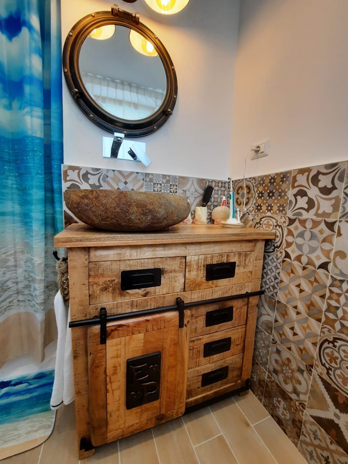 Un bagno con mobiletto in legno, lavandino, specchio e tenda da doccia.