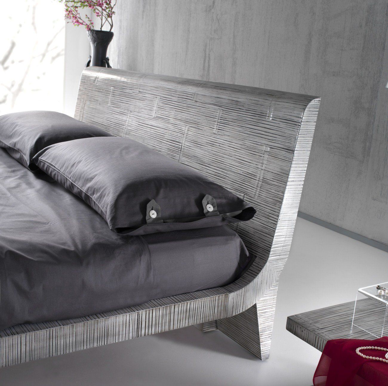 Un letto con lenzuola e cuscini grigi in una camera da letto